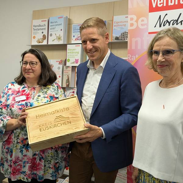 Die Vertreterinnen der Verbraucherzentrale und Markus Ramers stehen nebeneinander. Ramers hält eine Geschenkkiste in den Händen.