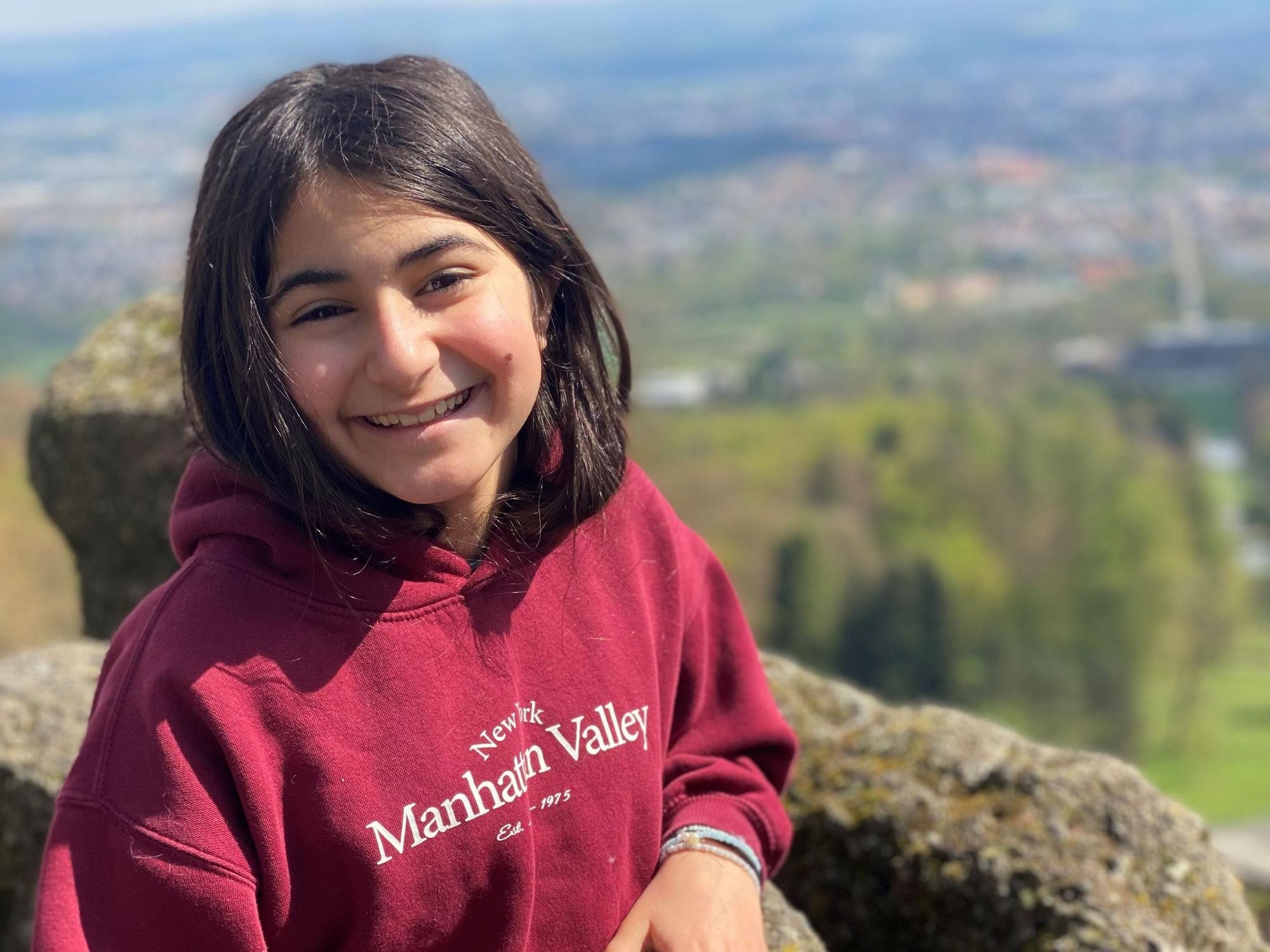 Auf dem Bild ist ein Mädchen in einem roten Sweatshirt zu sehen.