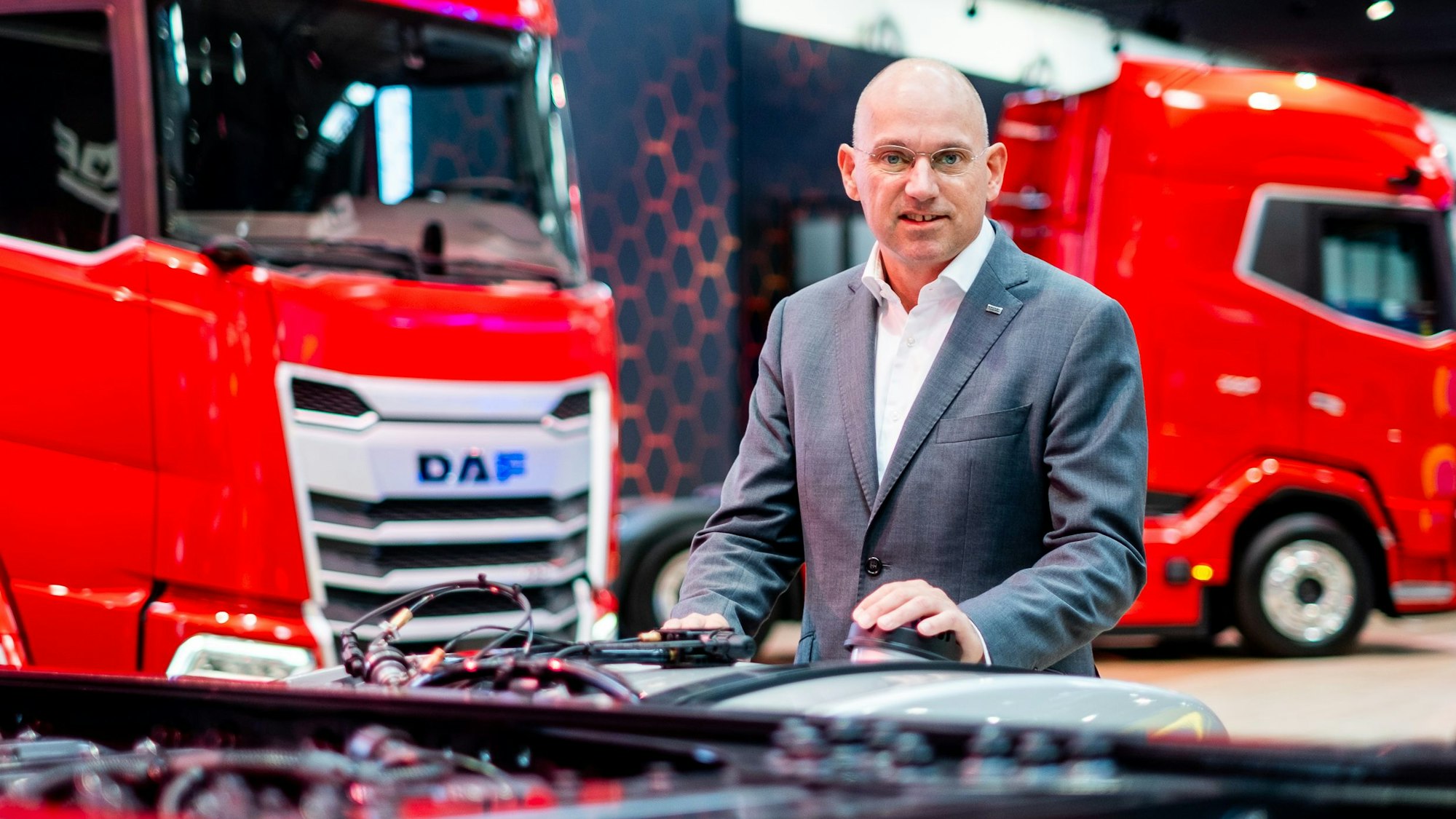 Auf dem Bild ist ein Mann vor roten Lkws zu sehen.