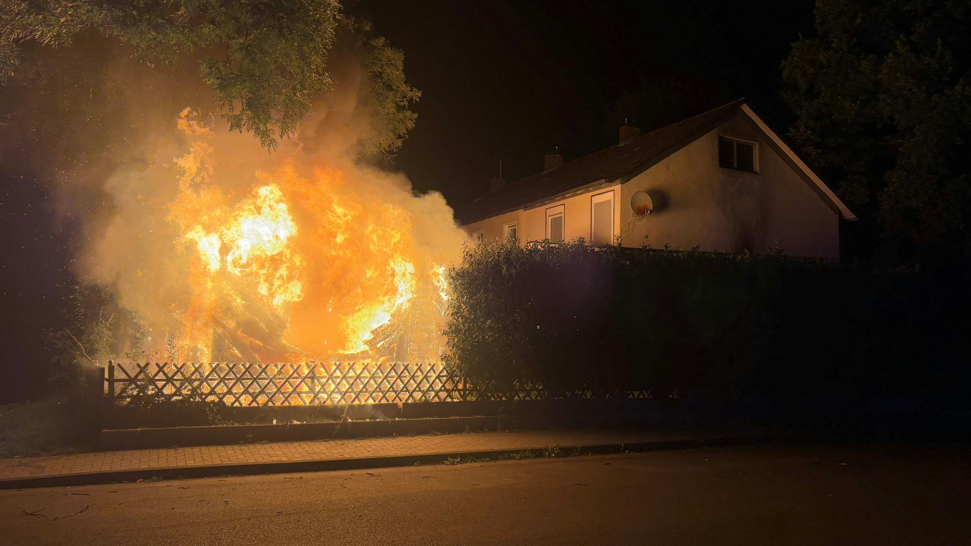 Eine Gartenlaube brennt lichterloh.