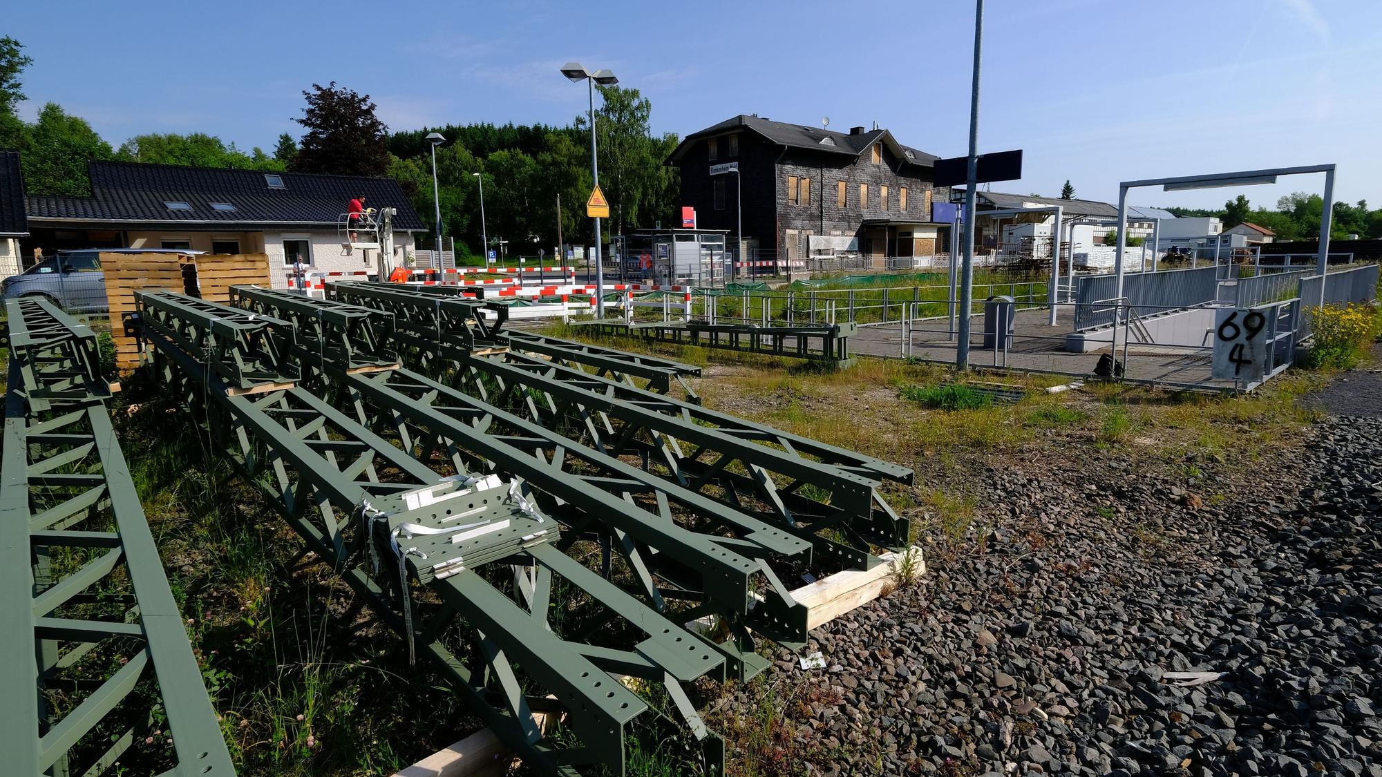 Oberleitungsmasten lagern vor dem Bahnhofsgebäude in Blankenheim (Wald).