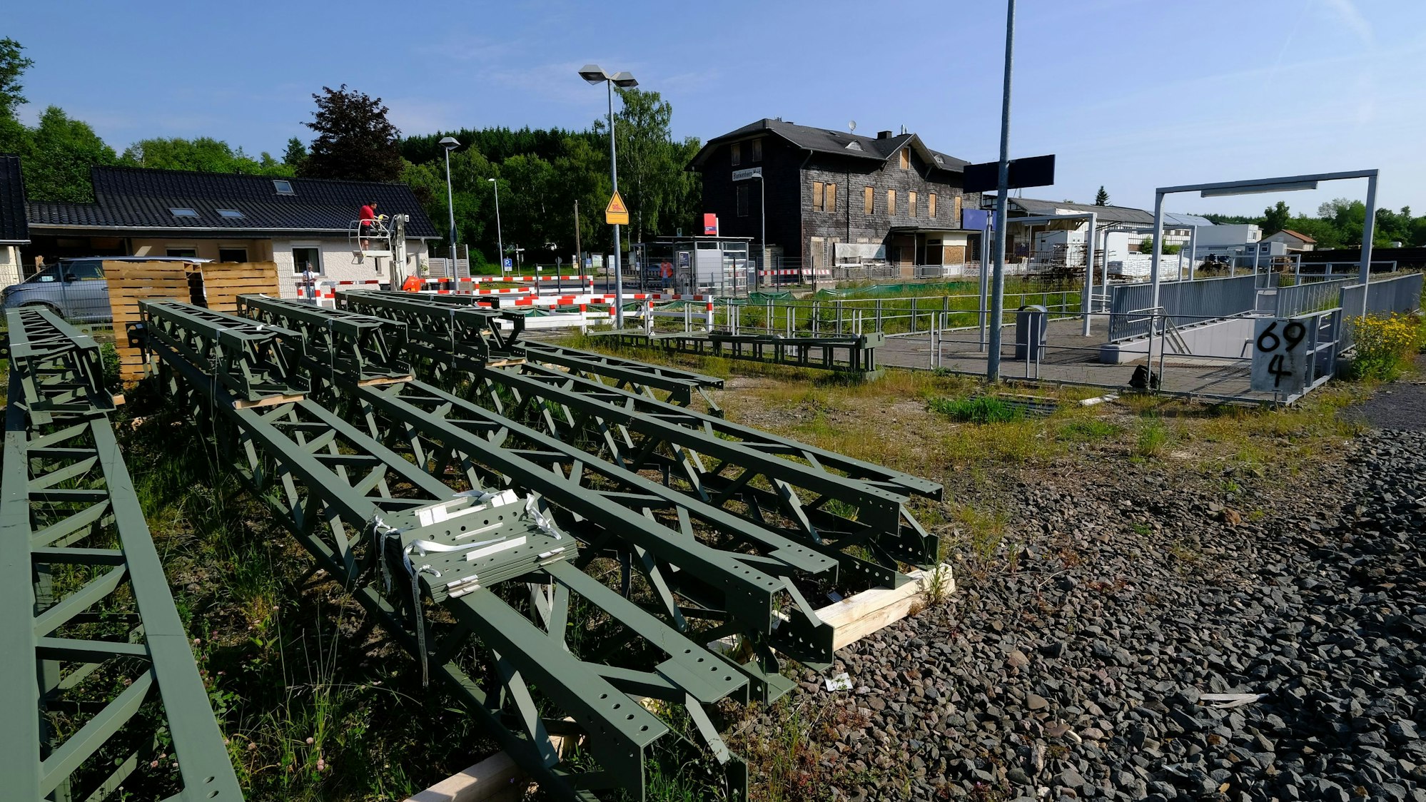 Oberleitungsmasten lagern vor dem Bahnhofsgebäude in Blankenheim (Wald).