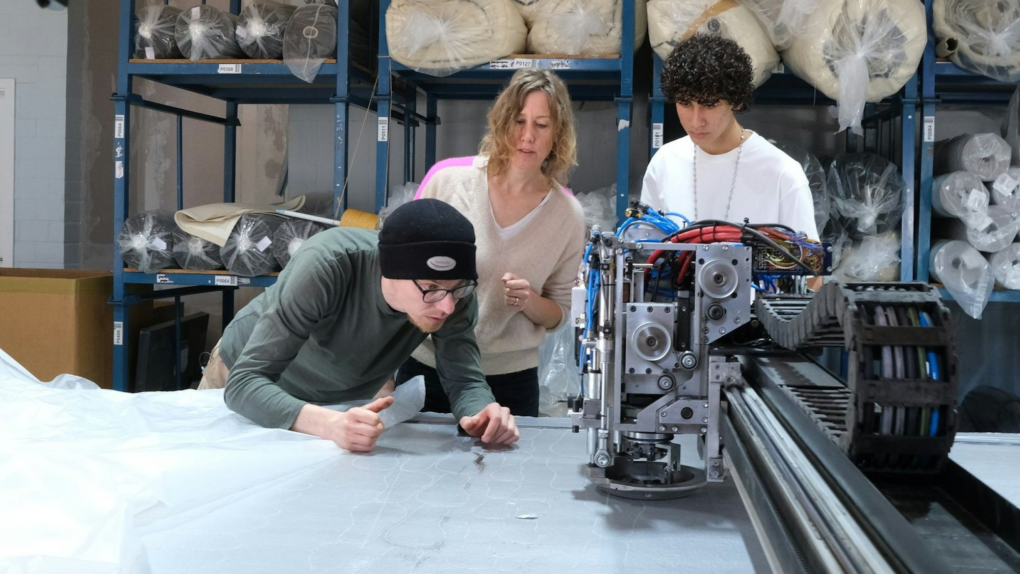 Bei Textilproduzent Marco Sheel (l.) prüfen Anna (M.) und Nevó Yona (r.) die Materialien für die Barfußschuhe.