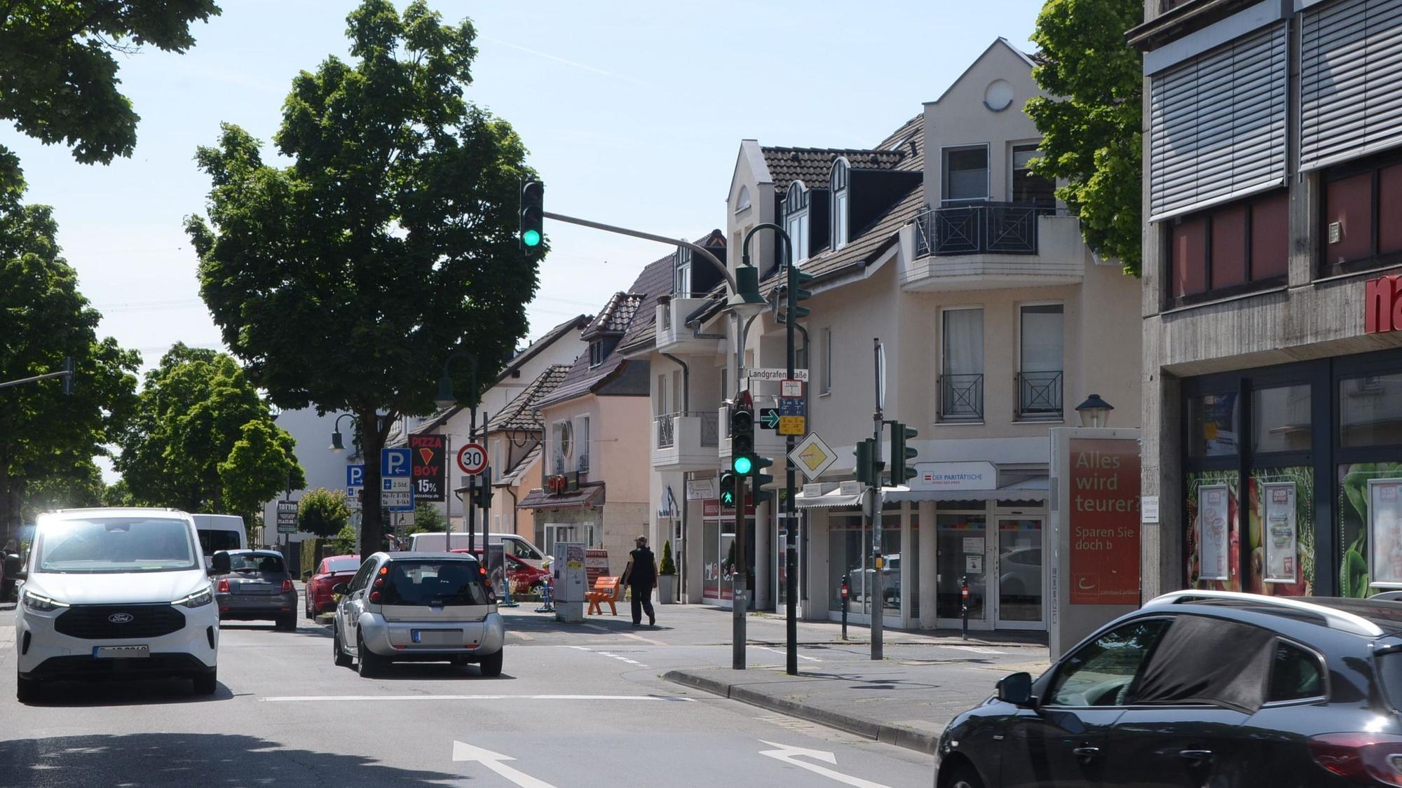 Eine Straßenkreuzung mit Ampel, Autos und Bäumen.