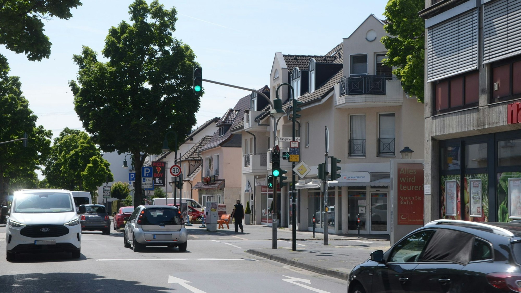 Eine Straßenkreuzung mit Ampel, Autos und Bäumen.