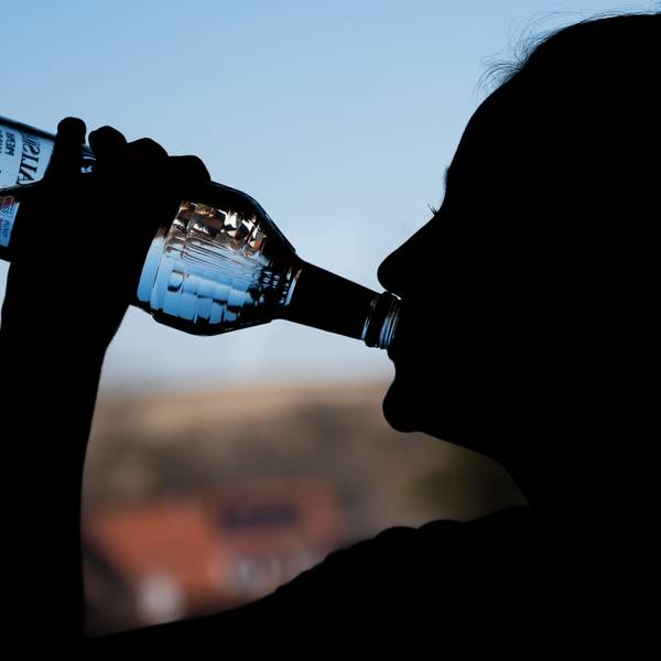 in Mädchen trinkt aus einer Flasche Alkohol.