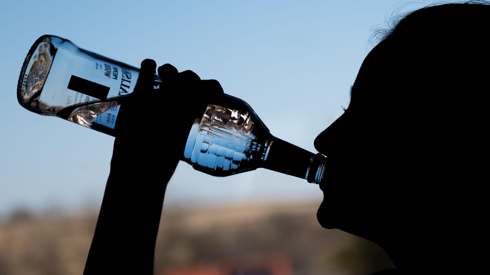 in Mädchen trinkt aus einer Flasche Alkohol.