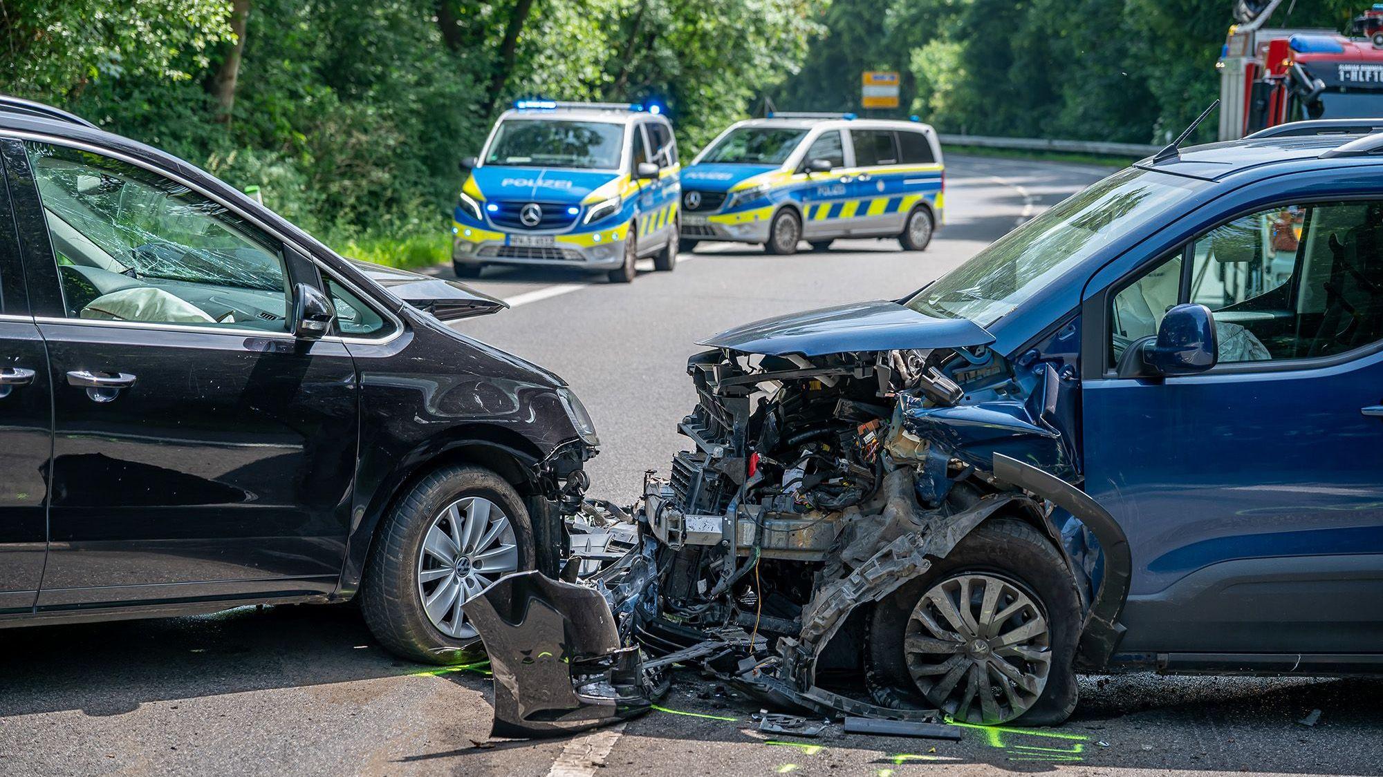 Zwei Unfallautos nach einem Frontalzusammenstoß. Im Hintergrund sind zwei Polizeiautos zu sehen.