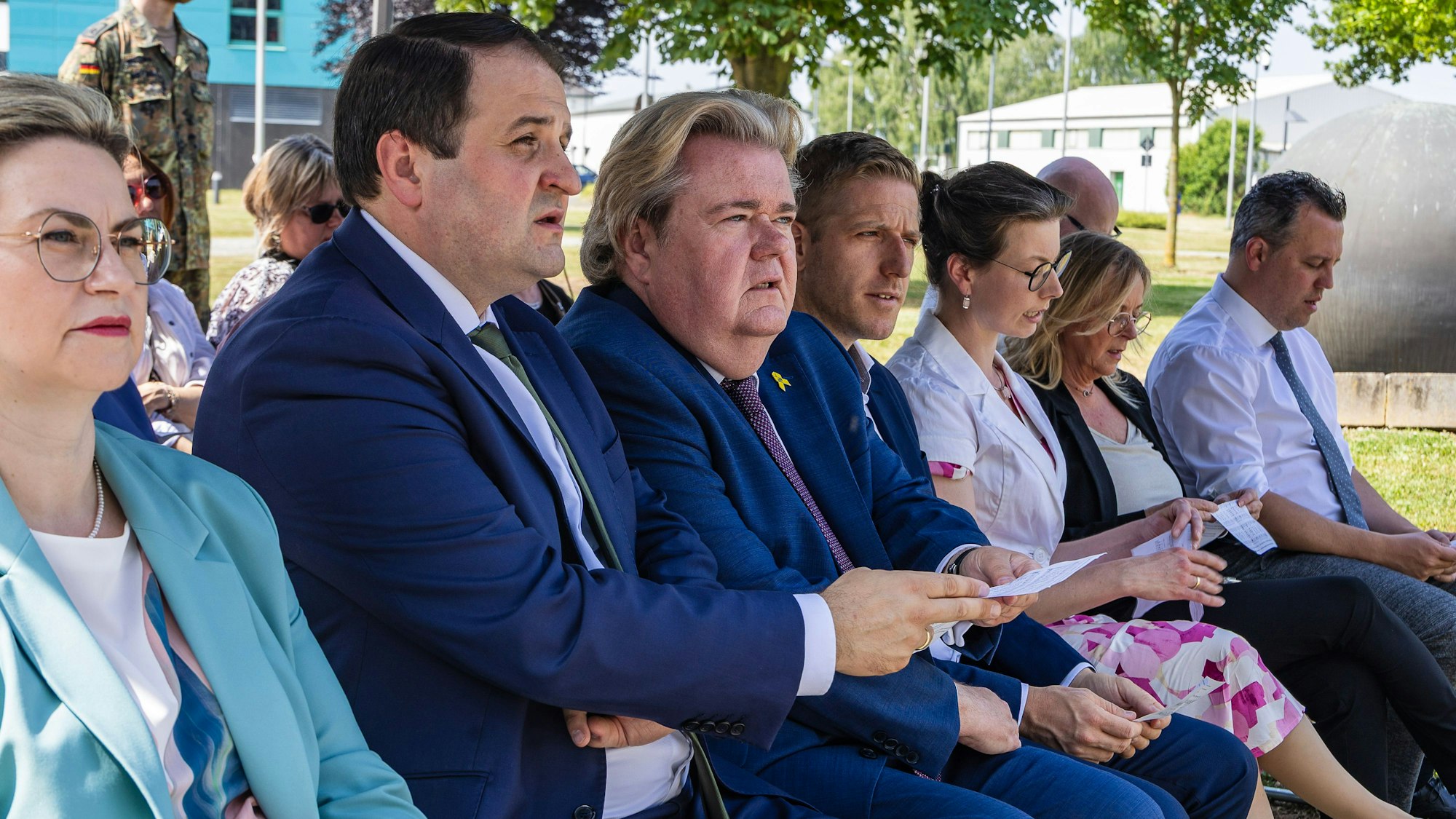 Die Gäste sitzen während der ökumenischen Andacht im Hof der Kaserne unter einem Zeltdach.