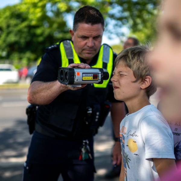 Das Bild zeigt einen Schüler, der mithilfe eines Polizisten durch ein Lasergerät schaut.
