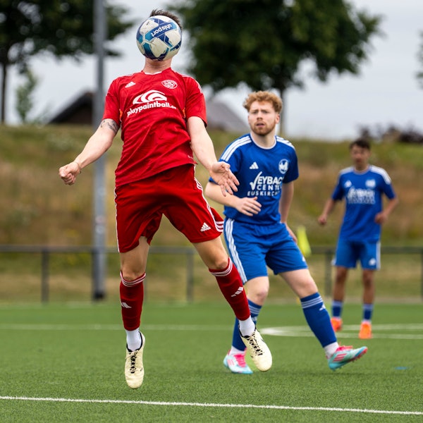 Das Bild zeigt einen Fußballer, der einen Ball direkt vor dem Kopf hat.