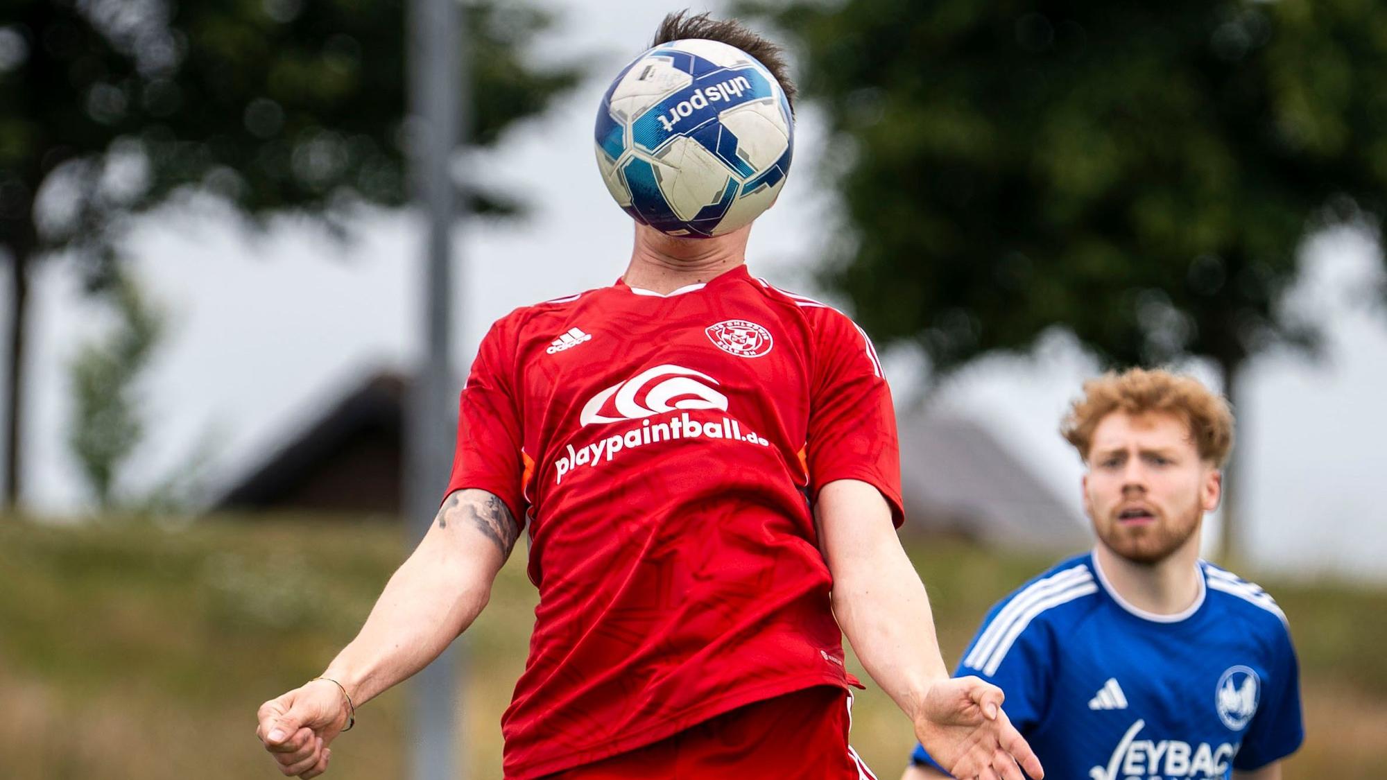 Das Bild zeigt einen Fußballer, der einen Ball direkt vor dem Kopf hat.