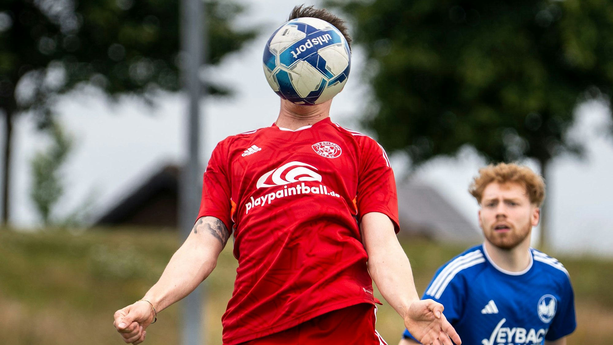 Das Bild zeigt einen Fußballer, der einen Ball direkt vor dem Kopf hat.
