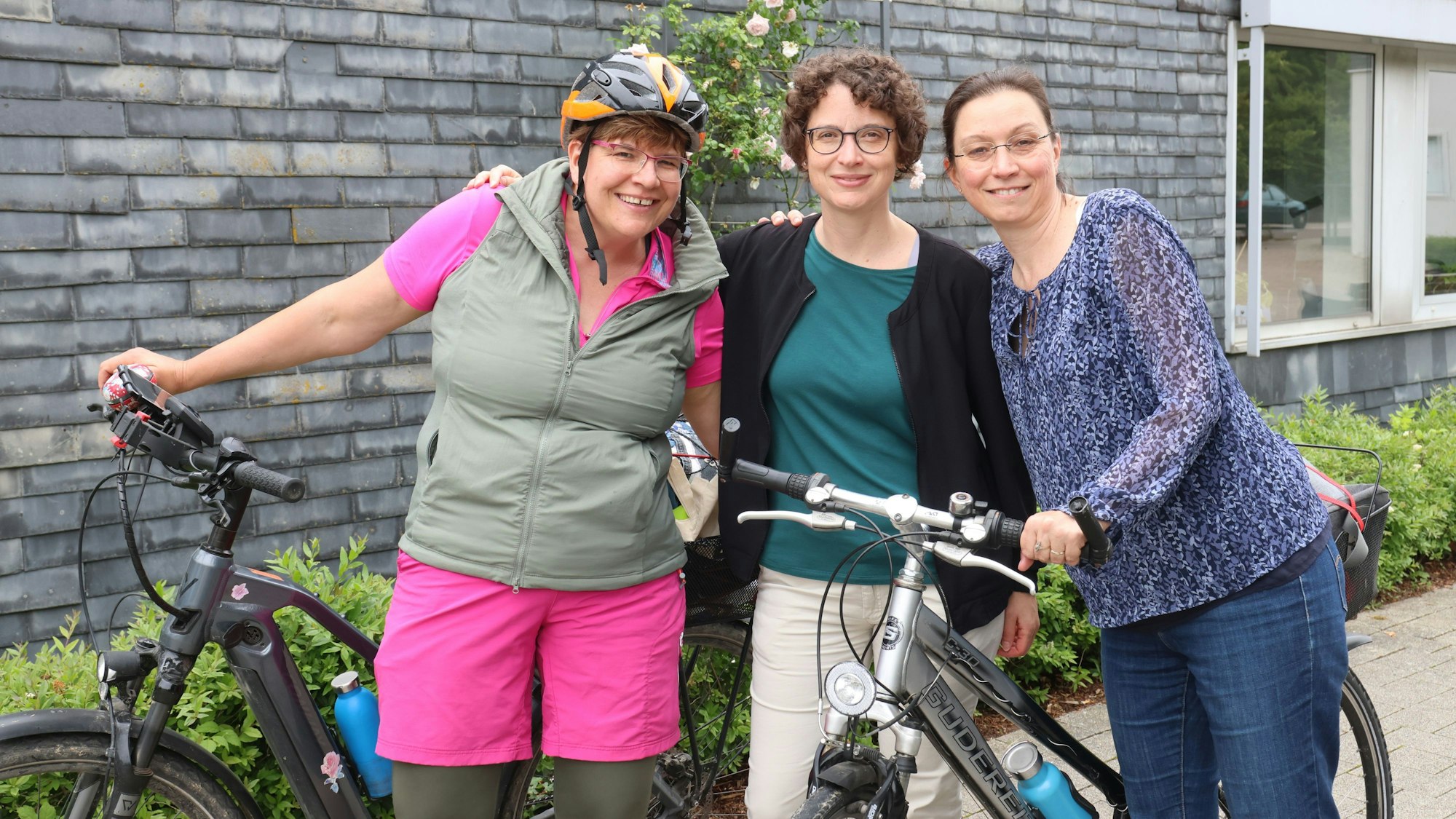 Drei Frauen stehen mit ihren Fahrrädern beisammen.