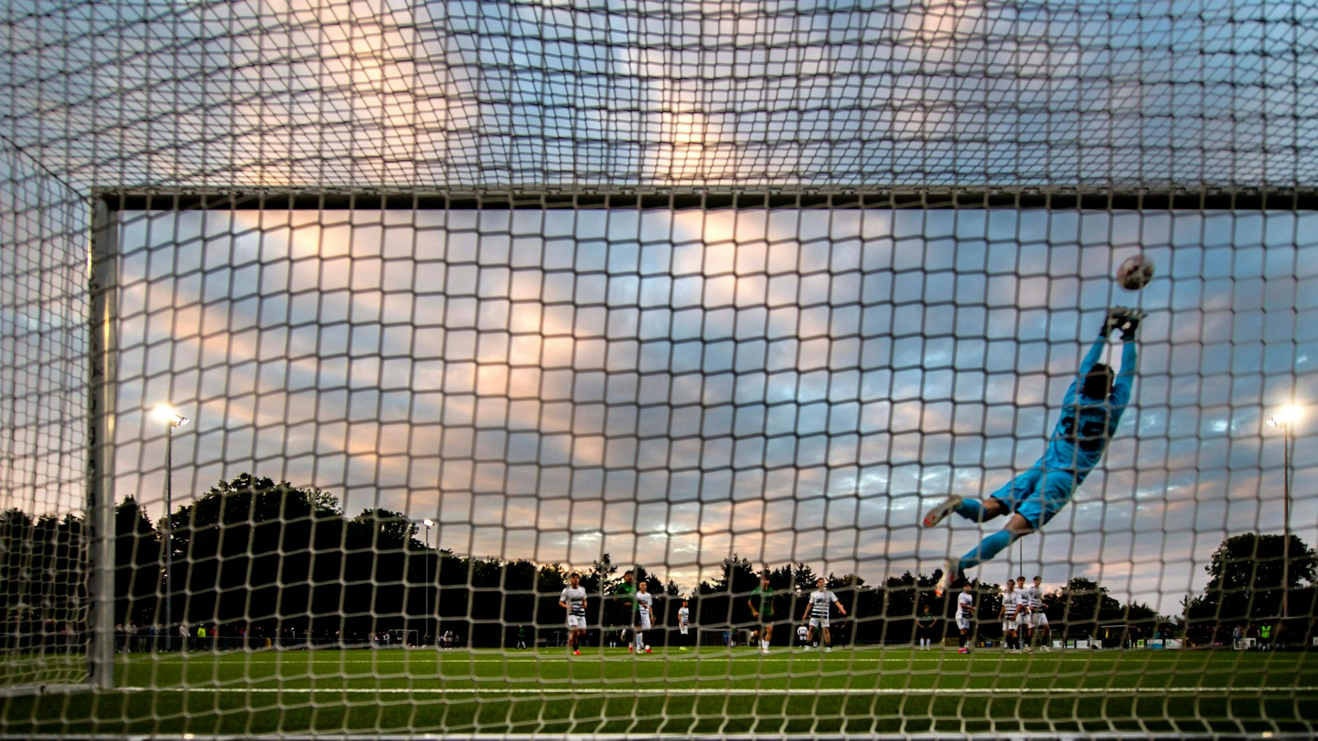 Das Bild zeigt einen Torwart, der mit einer Parade den Ball hält.