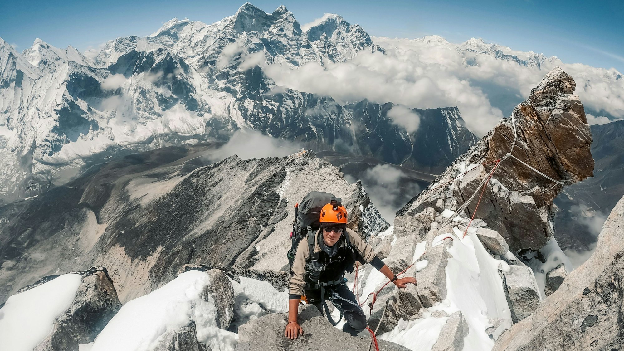 Frederik Tepe beim Aufstieg, hinter ihm ist ein atemberaubendes Bergpanorama zu sehen.