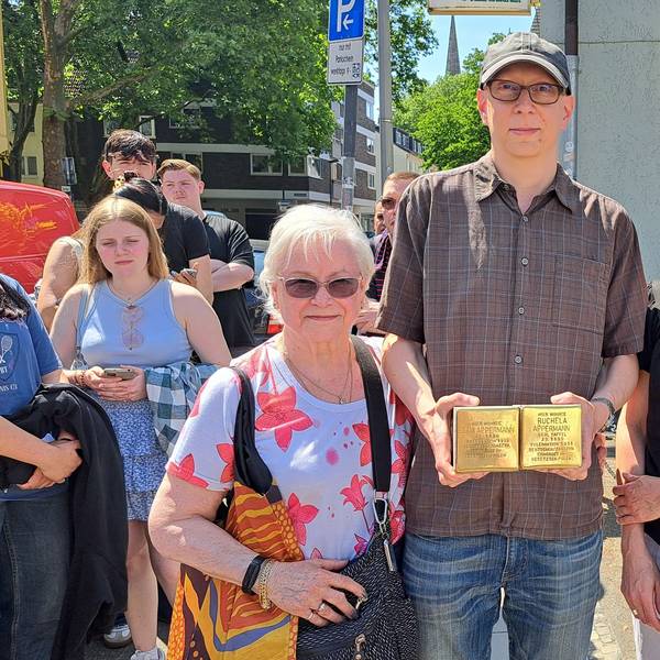 Zwei Frauen und ein Mann (Mitte) stehen nebeneinander. Der Mann hält zwei Stolpersteine in seinen Händen.