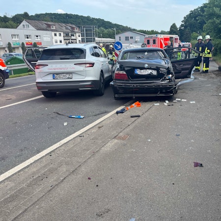 Zwei Unfallautos stehen in Kürten-Broich nebeneinander. Im Hintergrund sind Feuerwehrleute und Rettungsdienst zu sehen.