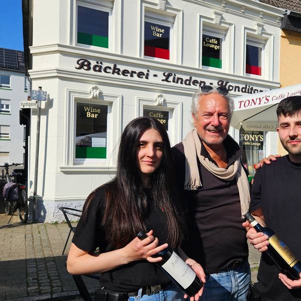 Zu sehen sind Margherita (l.) und Francesco Attrice (r.) mit jeweils einer Weinflasche in der Hand sowie in der Mitte ihr Vermieter Rolf Dieffendahl.