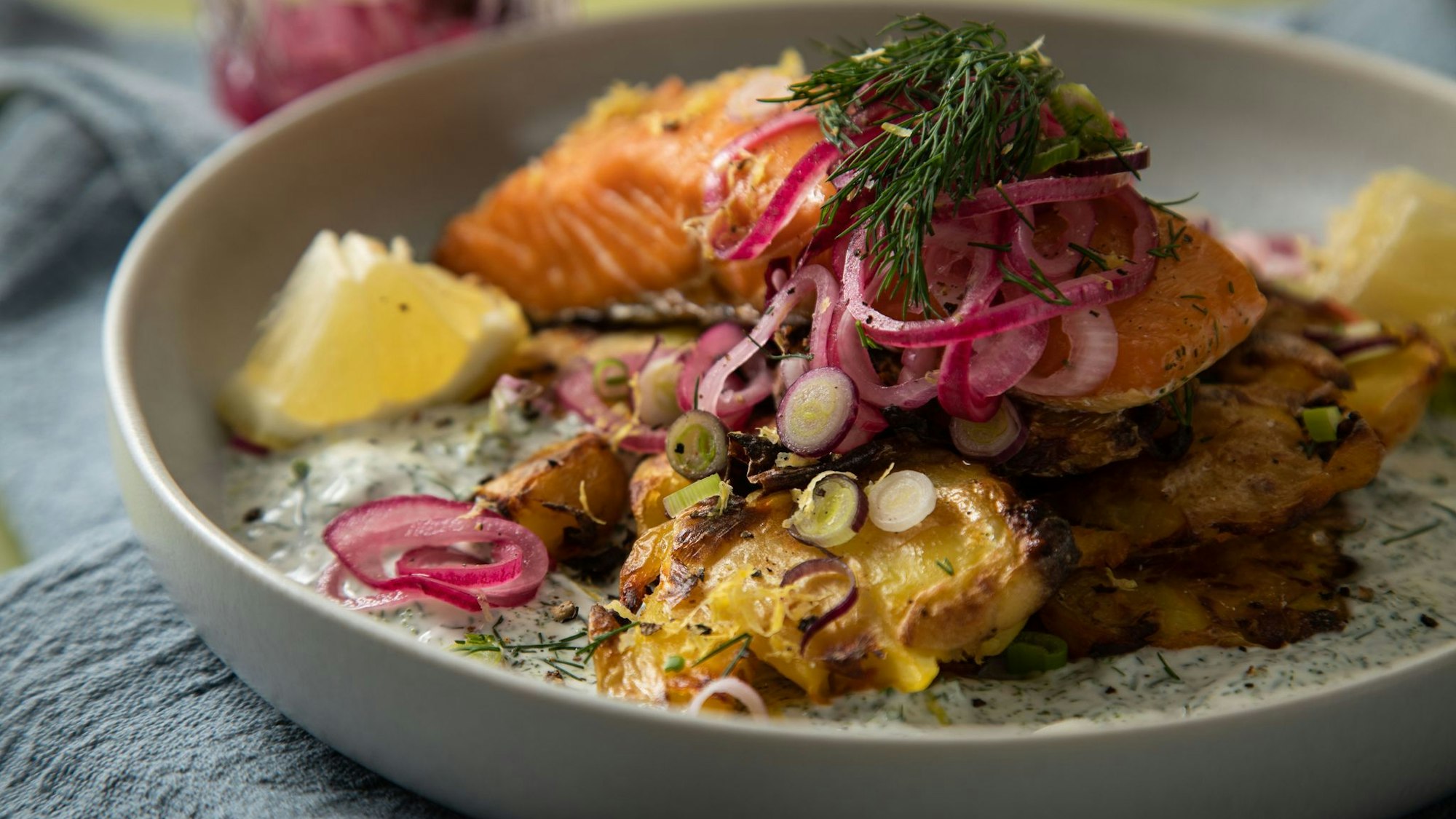 Eingelegte rote Zwiebeln toppen den Schweden-Salat mit crispy smashed Potatoes und Lachs.