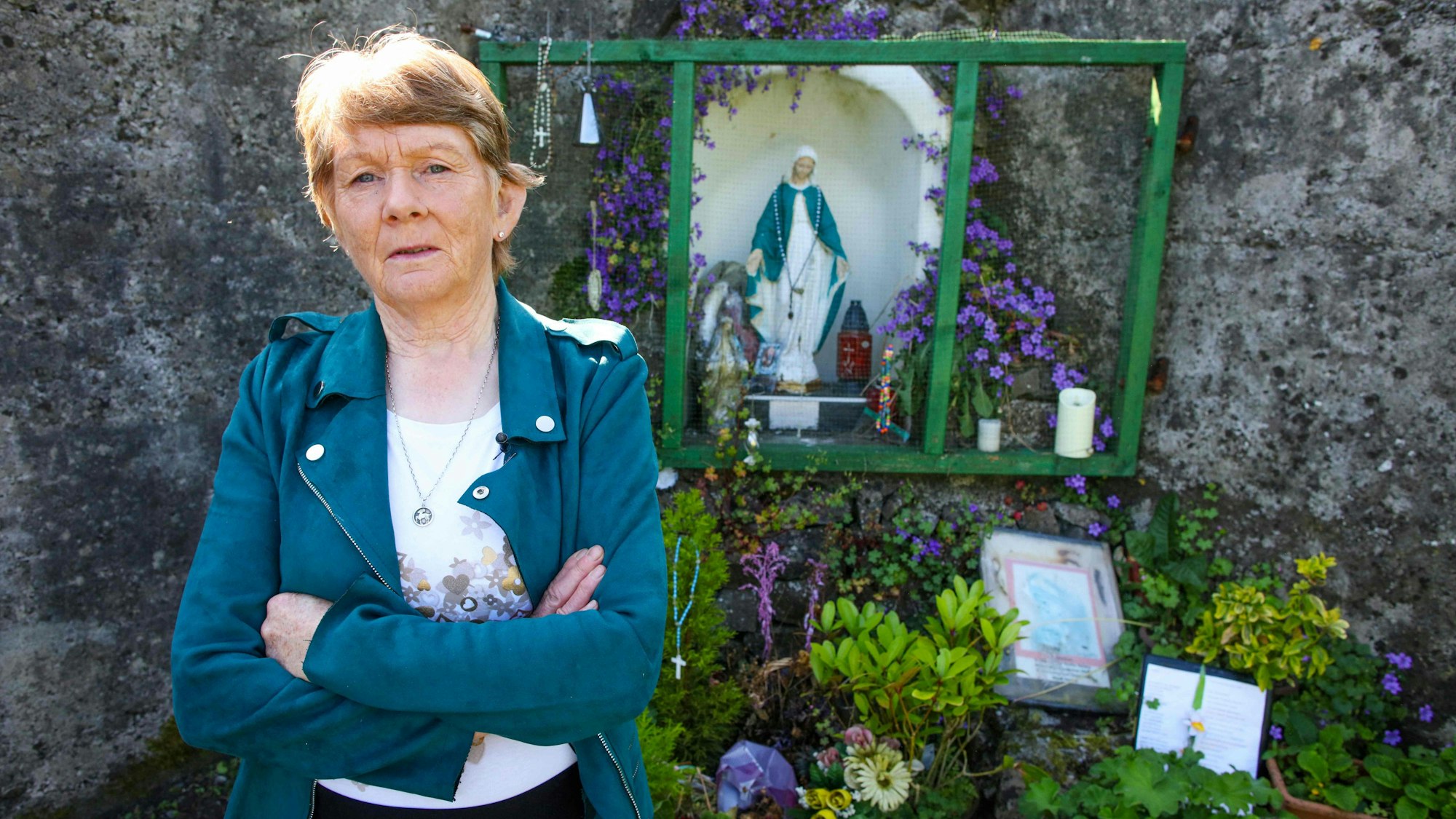 Catherine Corless steht mit verschränkten Armen vor der Gedenkstätte.