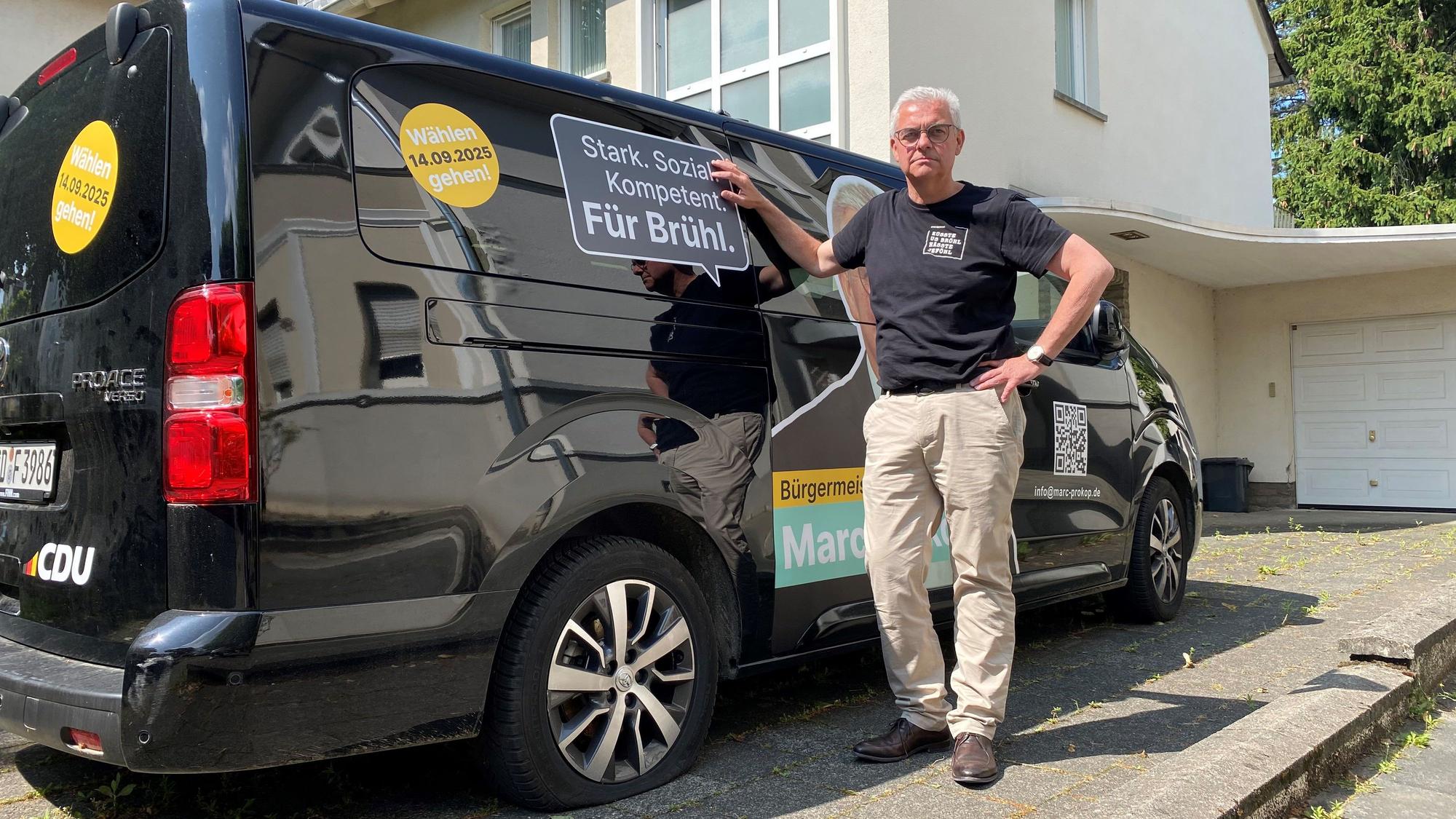 Zu sehen ist Marc Prokop vor dem Kleinbus, dessen Reifen platt sind.