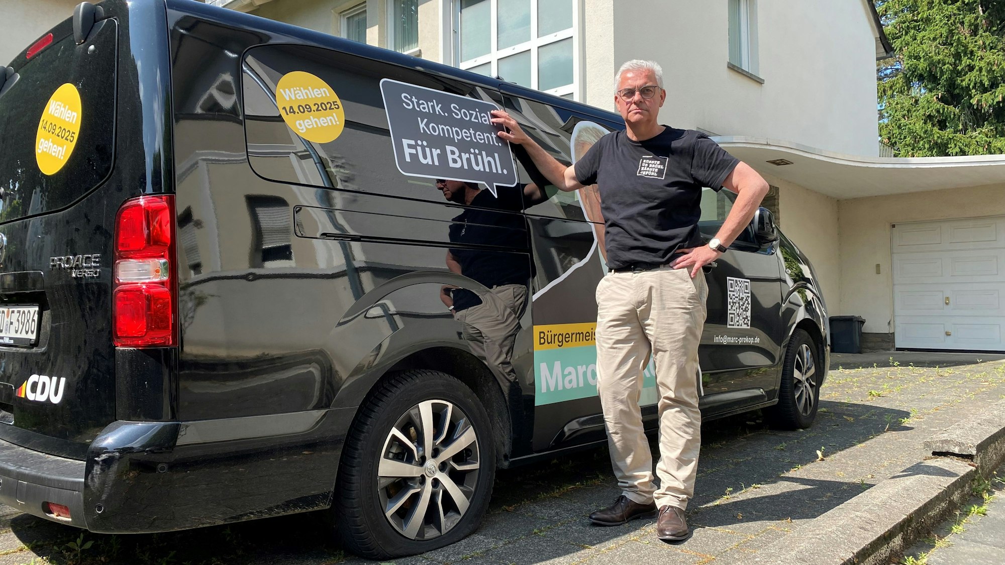 Zu sehen ist Marc Prokop vor dem Kleinbus, dessen Reifen platt sind.