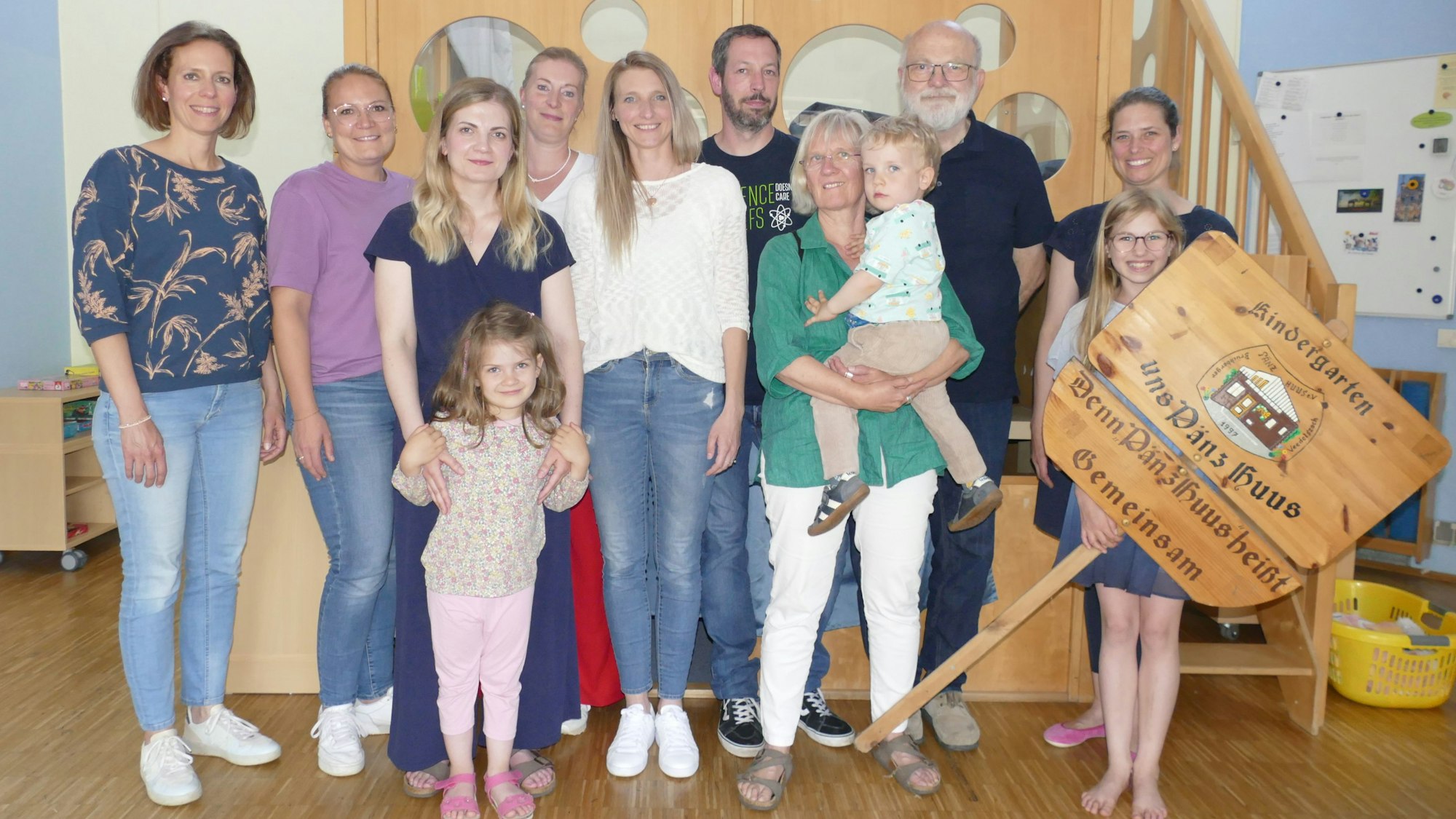 Männer, Frauen und Kinder im Turnraum einer Kindertagesstätte.