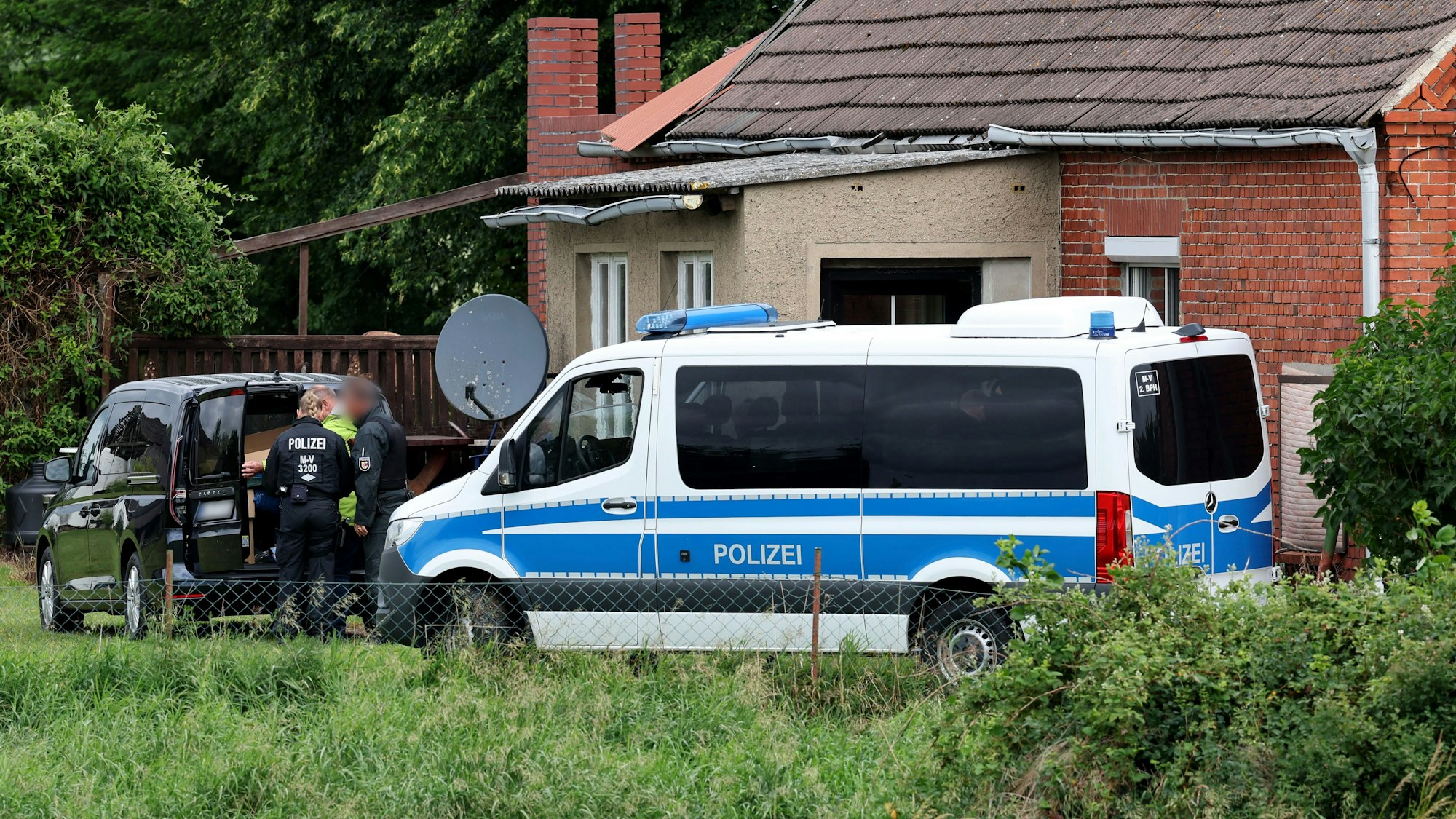 Ein Polizeifahrzeug steht auf dem Hof eines Grundstücks, das durchsucht wird. Bei einer Razzia im Reichsbürgermilieu ist das Haus eines 54 Jahre alten Mannes durchsucht worden.