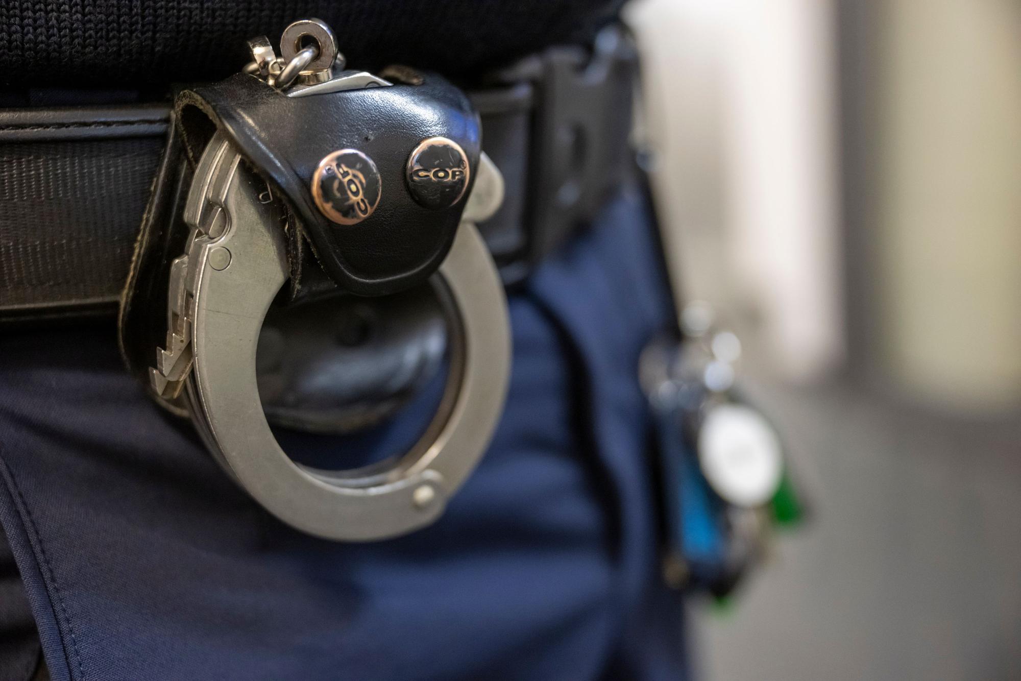 Das Bild zeigt Handschellen am Hosenbund eines Polizisten.
