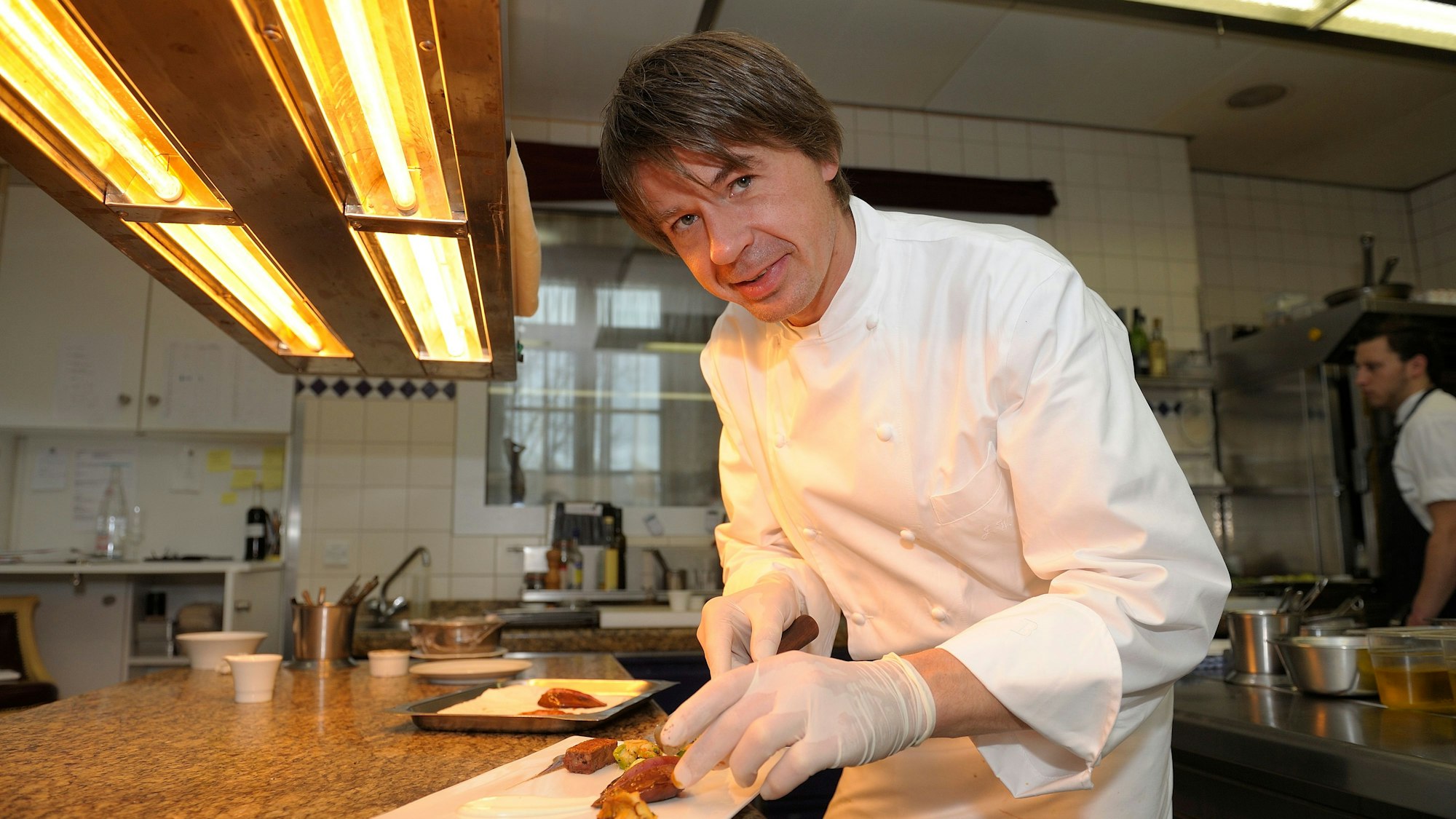 Joachim Wissler steht in der Küche und richtet einen Teller an.