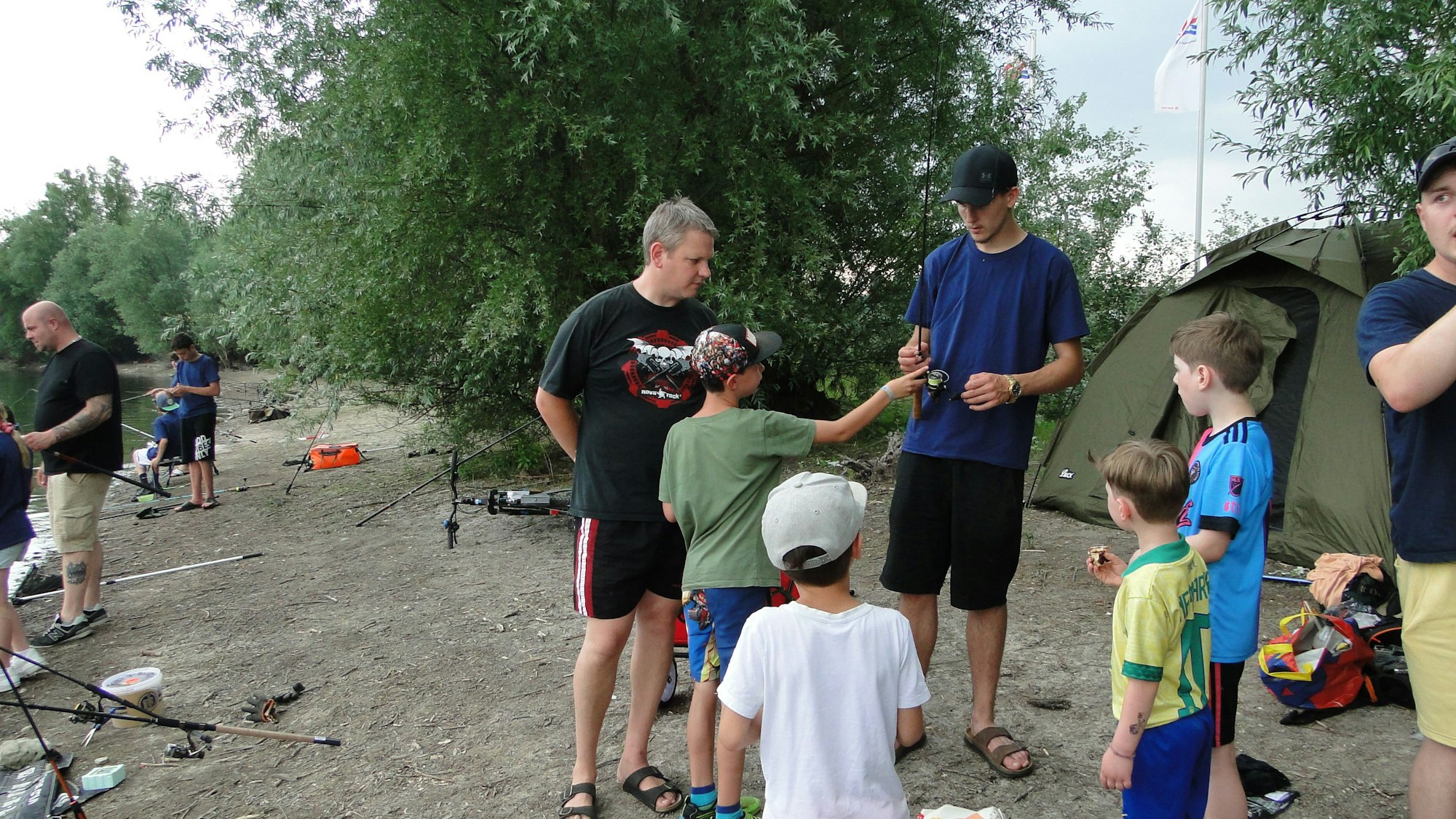 Kinder und Erwachsene stehen am Ufer eines Sees.