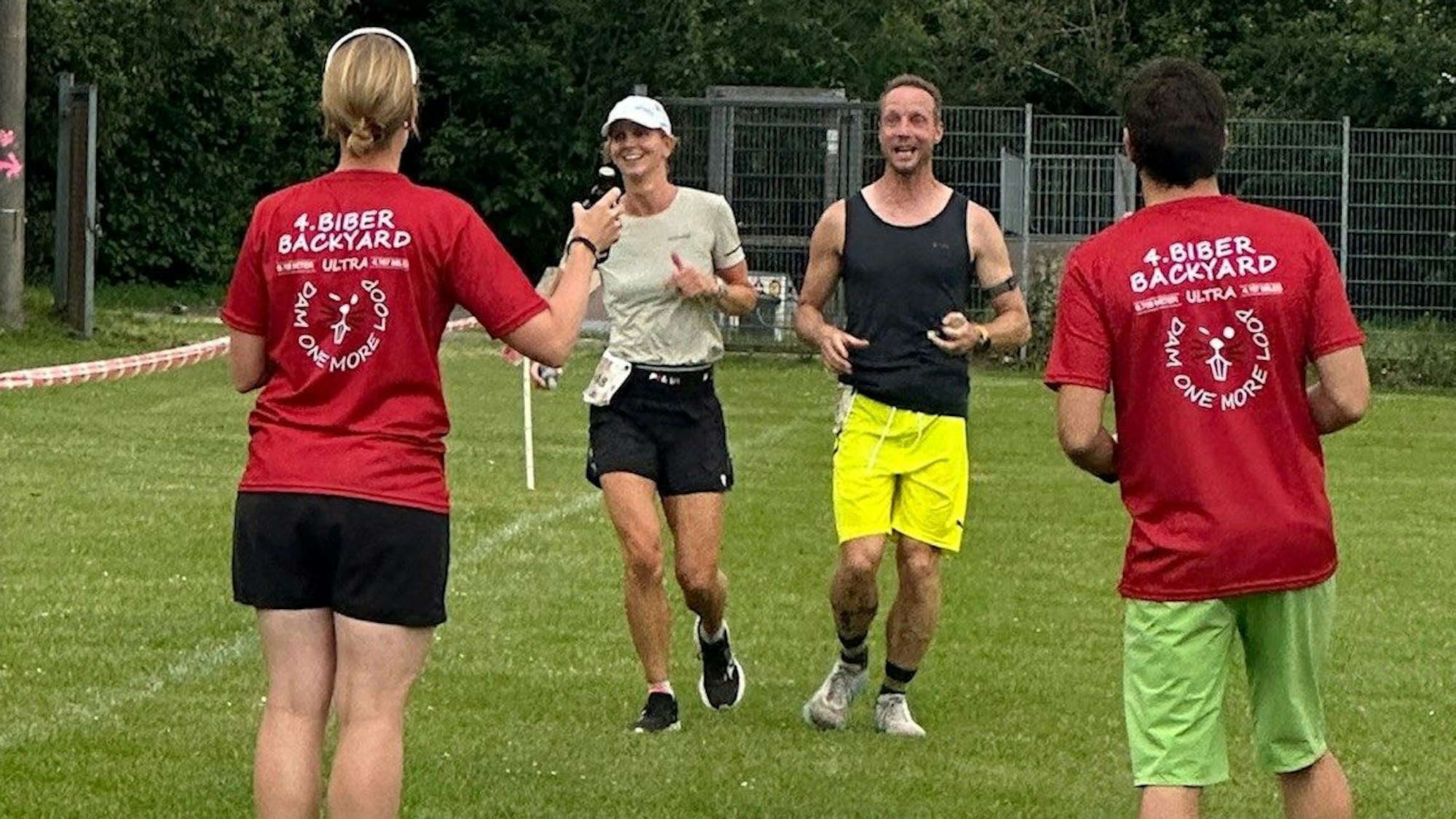 Christine Becker und Markus Habermann laufen nebeneinander ins Ziel, wo ein Mann und eine Frau in Biber-Backyard-T-Shirts warten.