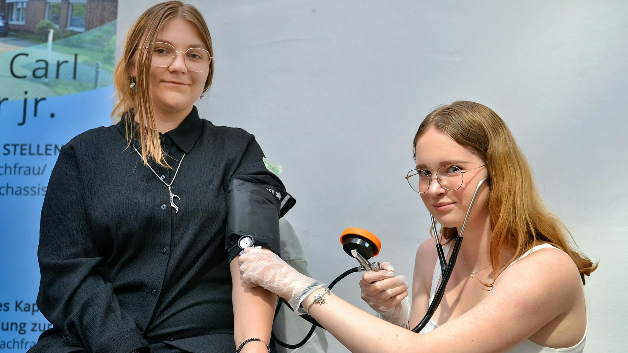 Das Bild zeigt zwei Jugendliche. Die eine misst der anderen den Blutdruck.