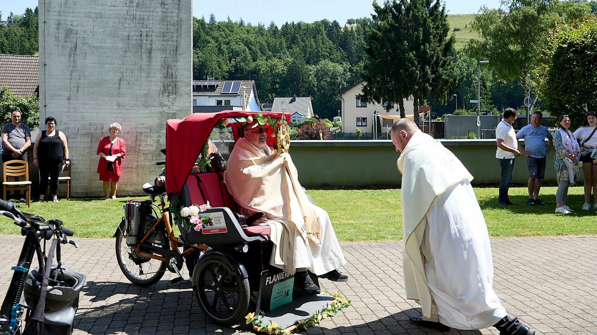 Das Bild zeigt den Diakon, der in einer Fahrradrikscha sitzt.