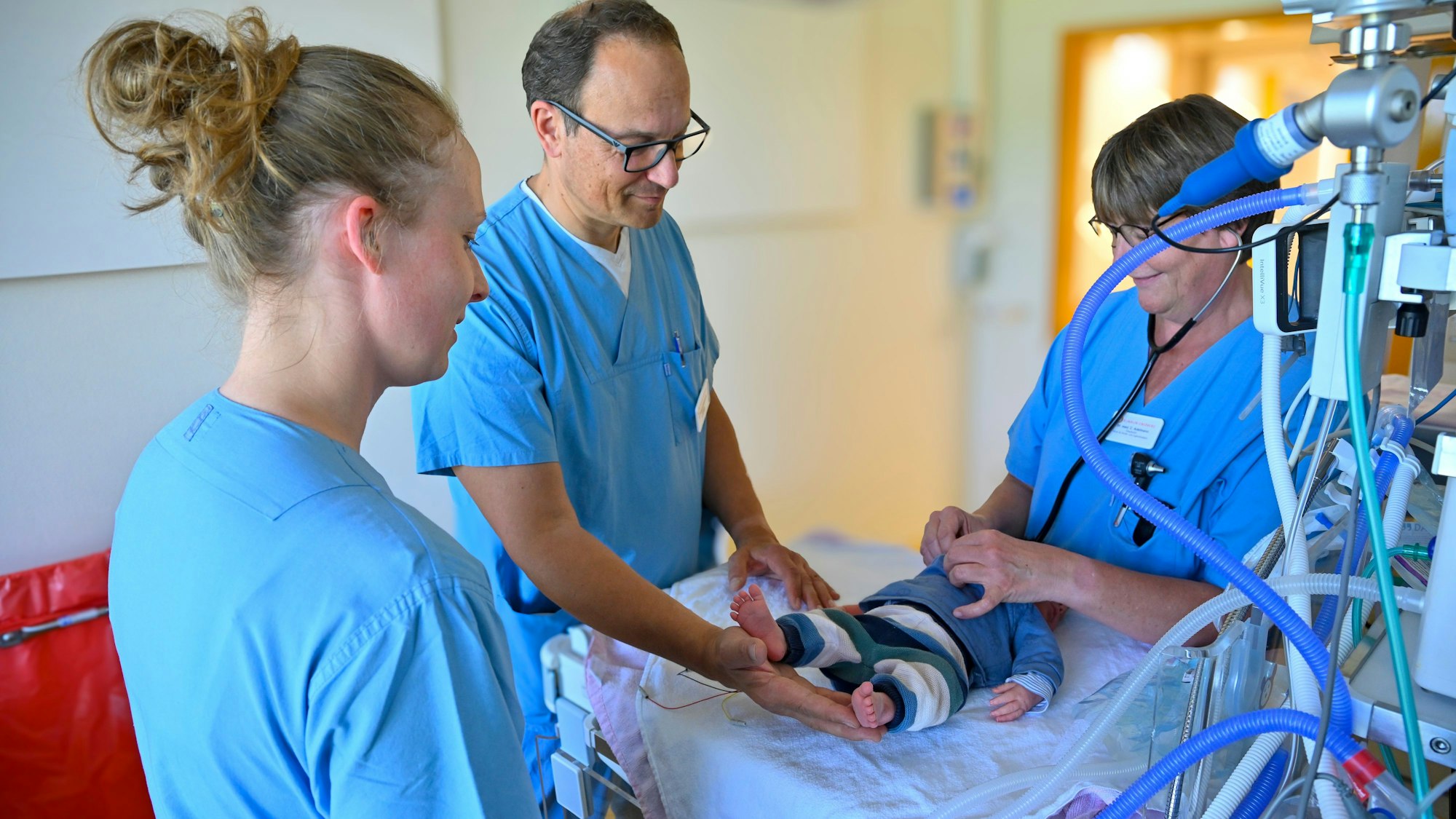 Chefarzt Roland Adelmann mit zwei Mitarbeiterinnen bei der Versorgung eines Frühchens.