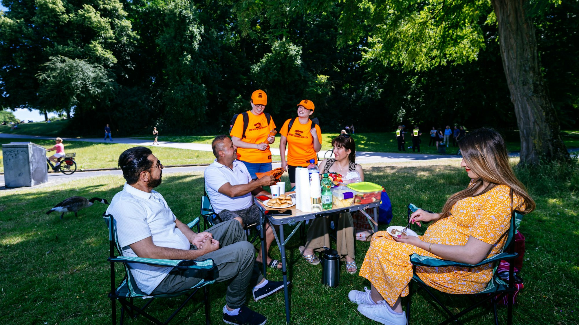 Die Grill-Scouts Vera Drewke (l.) und Nisa Bagci bieten einer Gruppe mit Grill ihre Abfalltüten an.
