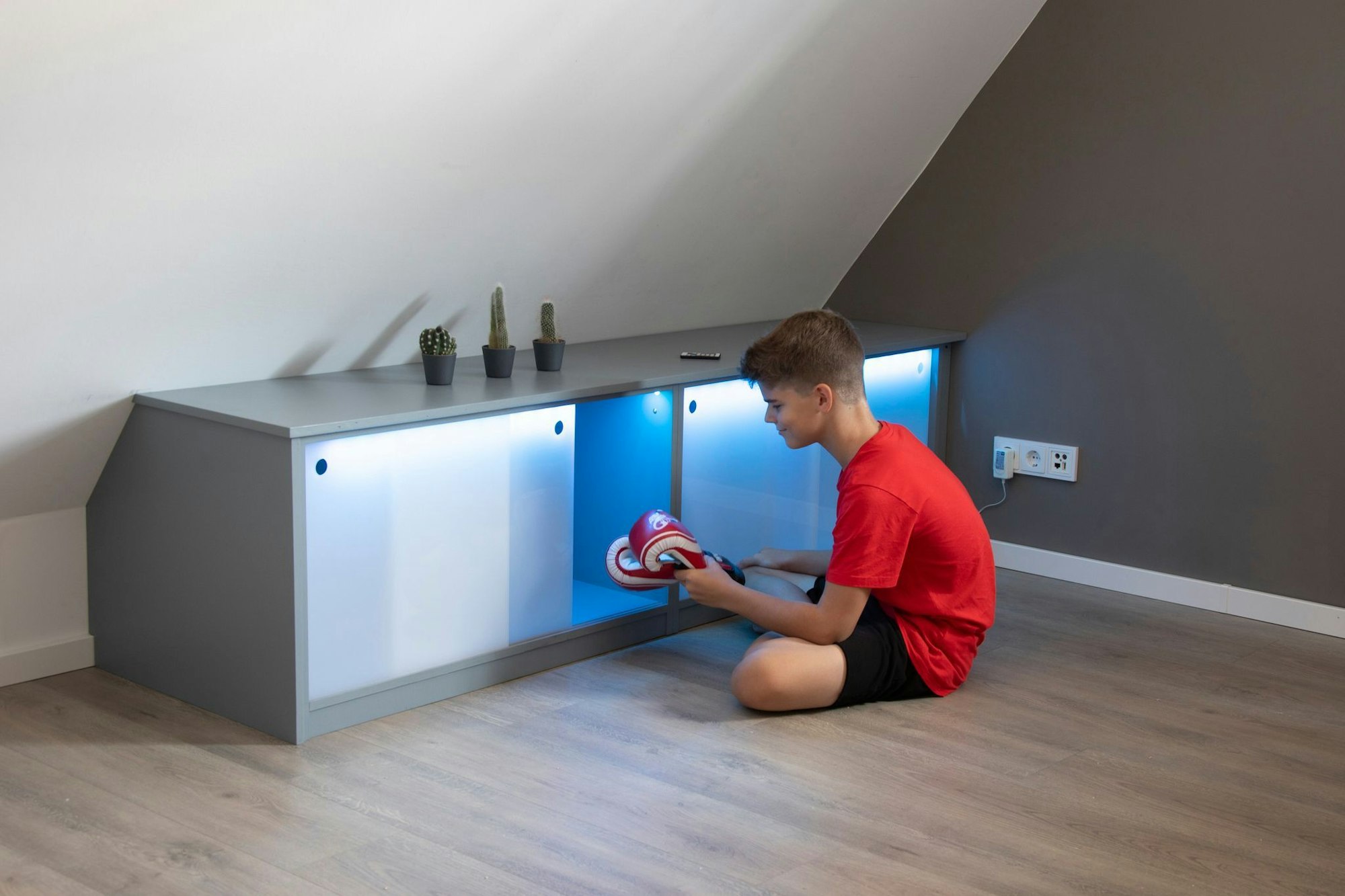 Stauraum unter der Dachschräge: Die Schiebetüren aus Acrylglas werden mit Hilfe eines LED-Bandes von innen indirekt beleuchtet.