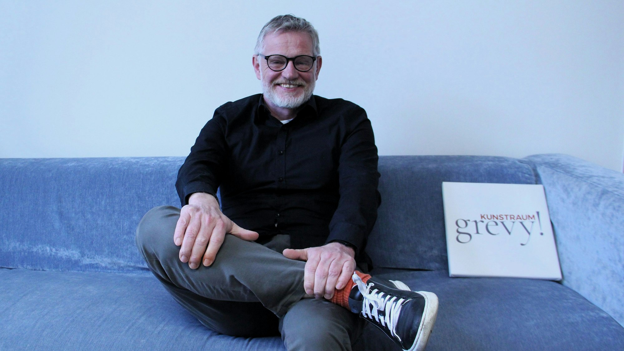 Ein Mann sitzt auf einem blauen Sofa.