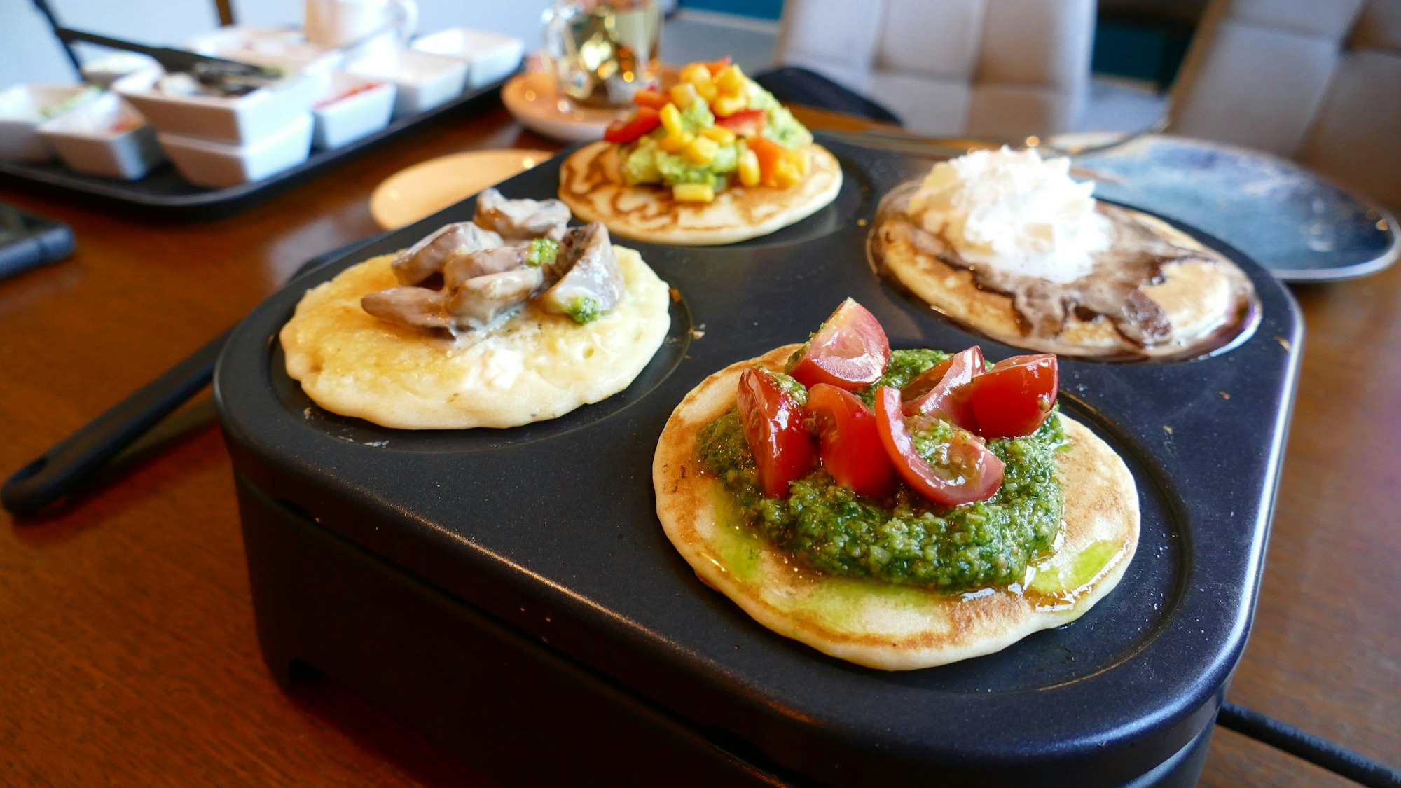 Vier Pancakes liegen auf einer mobilen Garplatte, belegt mit süßen und herzhaften Zutaten.