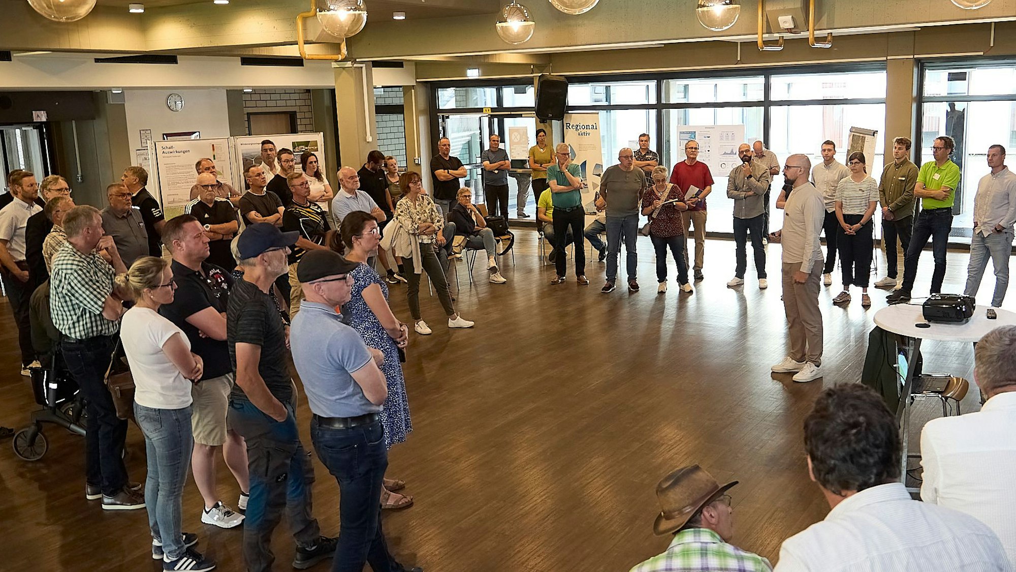 Zahlreiche Menschen stehen in der Aula der Hauptschule in Hellenthal im Kreis.
