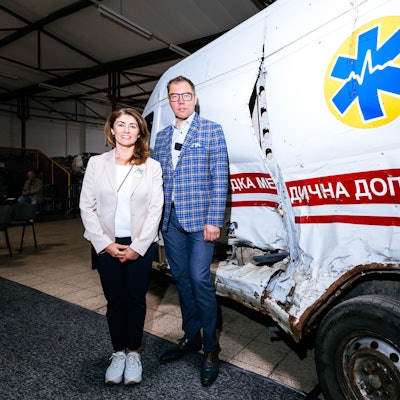 Vor einem zerstörten Rettungswagen: Linda Mai und der Botschafter der Ukraine, Oleksij Makejew.