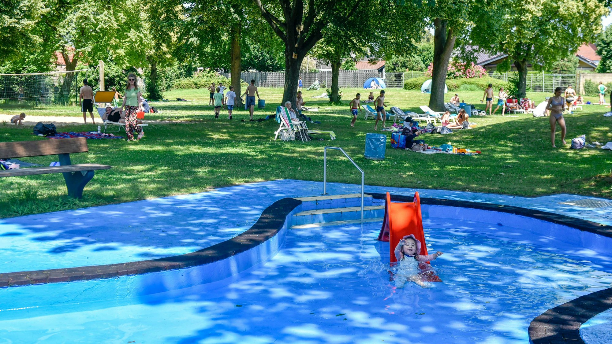 Zu sehen ist ein Schwimmbecken, dahinter eine Liegewiese.