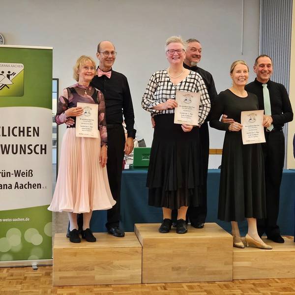 Uwe und Vera Bartsch stehen auf dem Podium ganz oben. Vera Bartsch hÀlt die Urkunde in die Kamera.