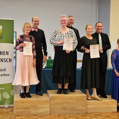 Uwe und Vera Bartsch stehen auf dem Podium ganz oben. Vera Bartsch hält die Urkunde in die Kamera.