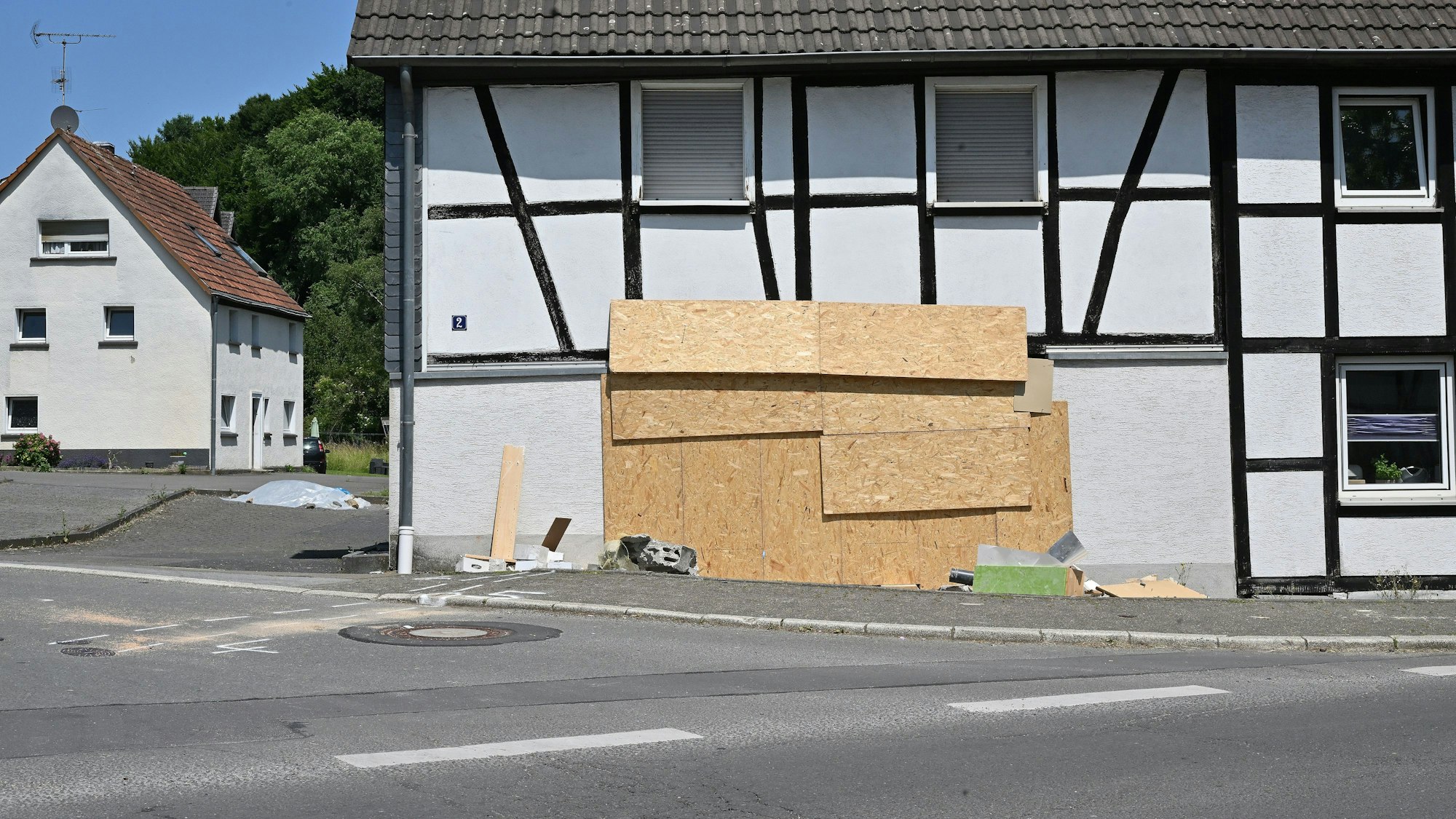 Das Haus steht am Straßenrand. Das Loch in der Wand ist durch Holzplatten geschlossen.