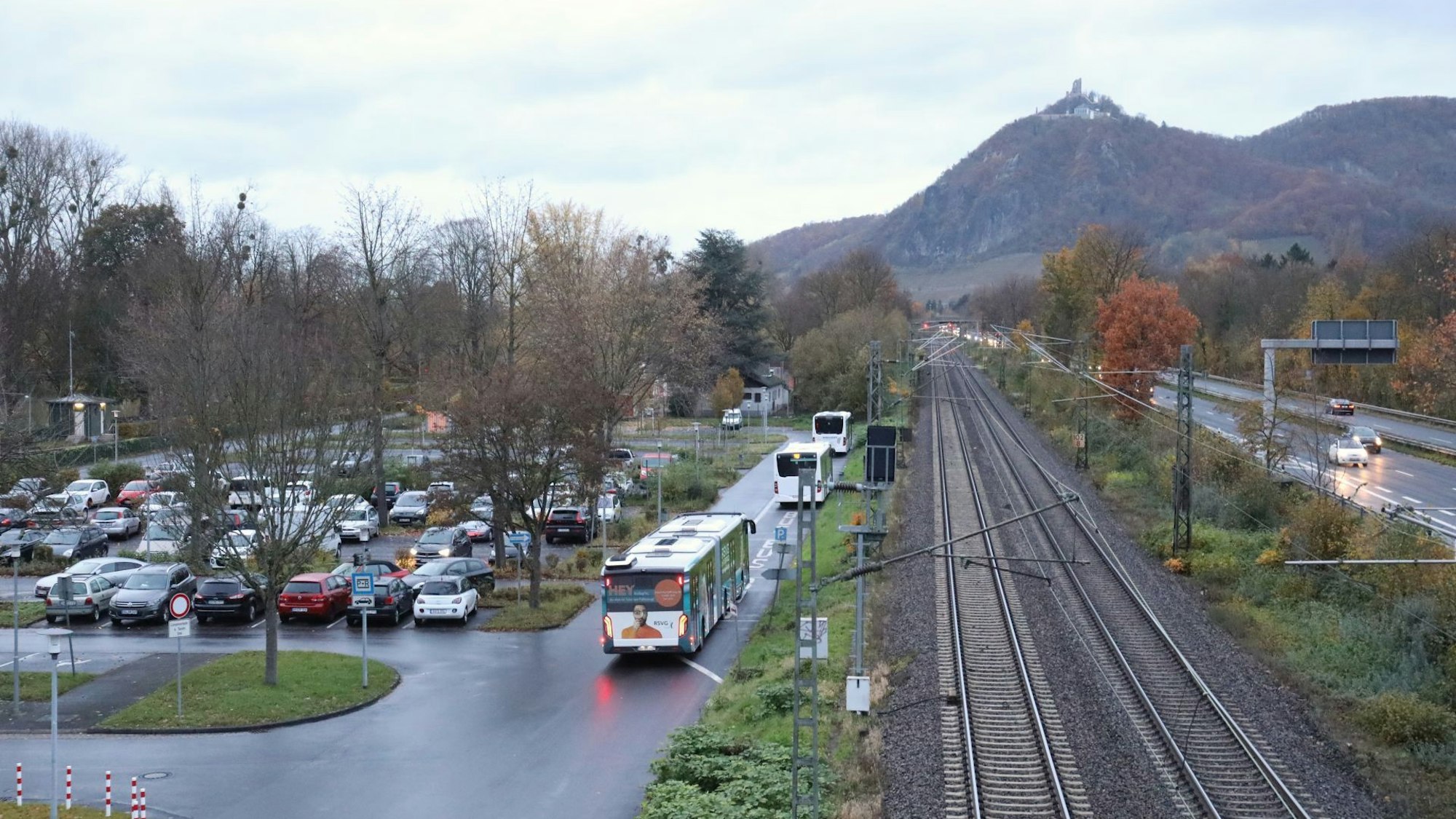 Ein Großraumparkplatz mit Pkw und wartenden Linienbusse, rechts eine Bahntrasse und die Bundesstraße 42.
