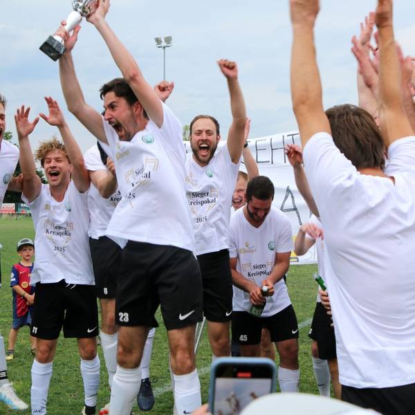 FlaKi-Kapitän Lukas Mager reckt den Pokal in die Höhe. Er und seine Mitspieler jubeln.