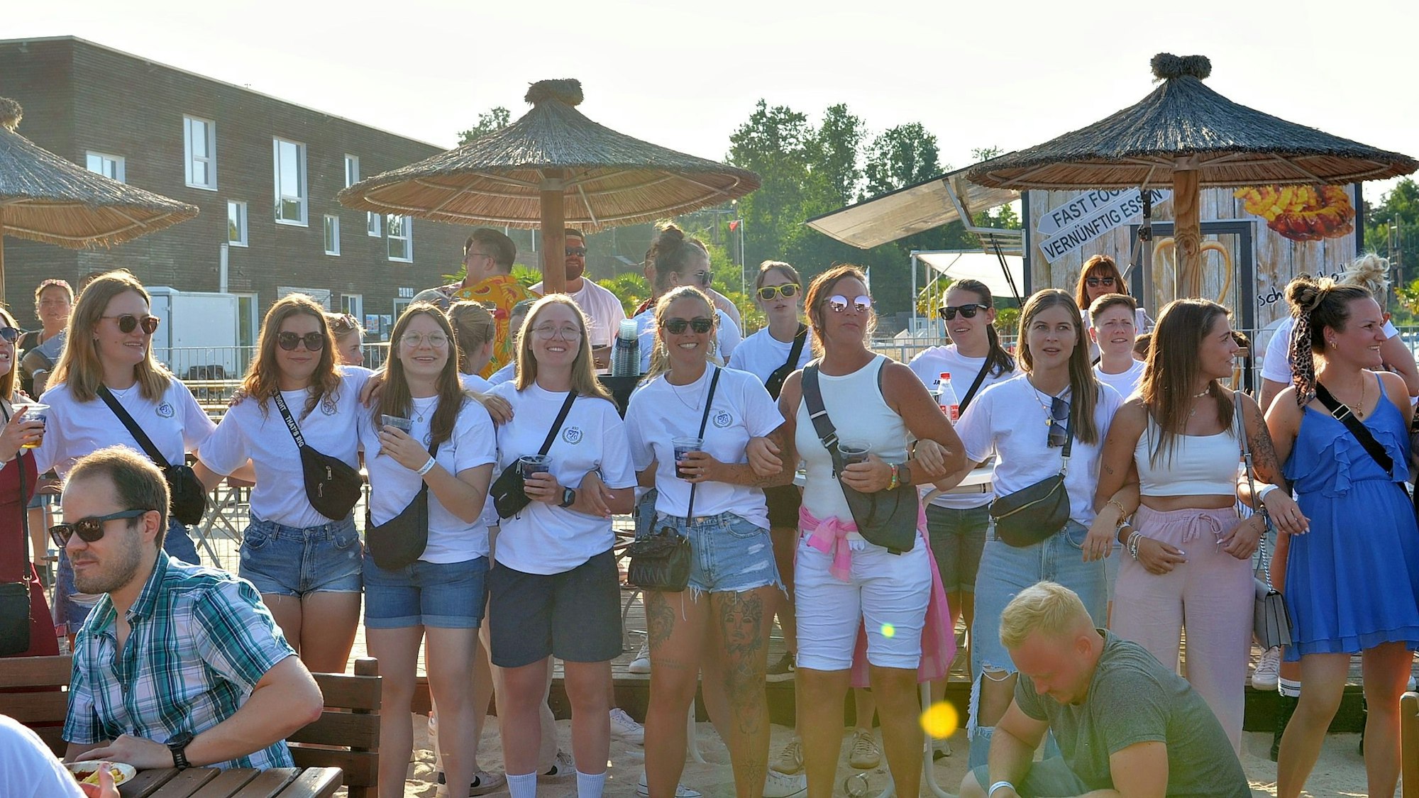 Das Bild zeigt zwei Reihen von jungen Frauen, die sich untergehakt haben. Die meisten tragen weiße T-Shirts.