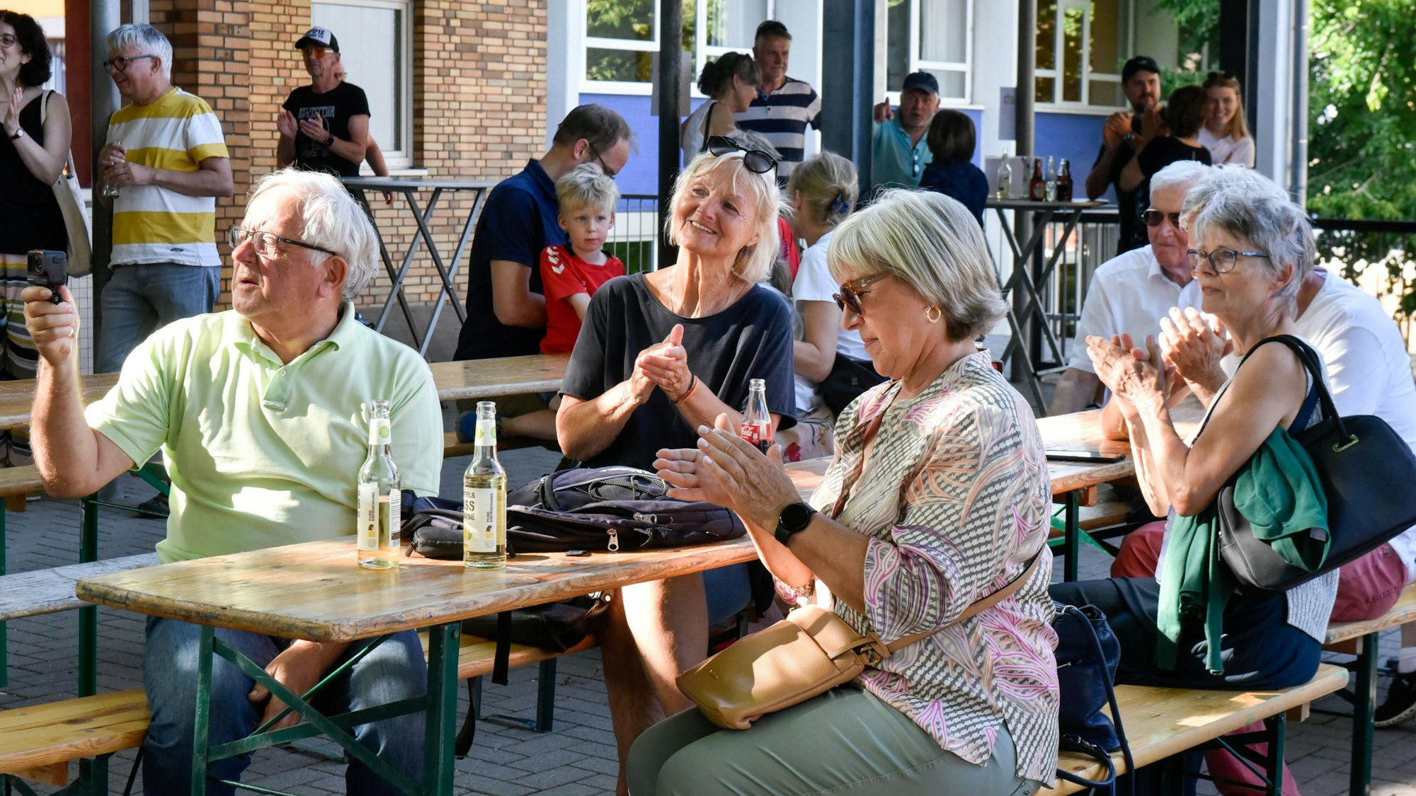 Zu sehen sind die Besucher eines Biergartens, die zur Musik klatschen.